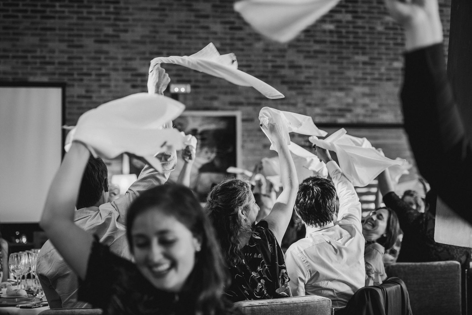 Dancing and celebrations captured in black and white at an indoor wedding reception.