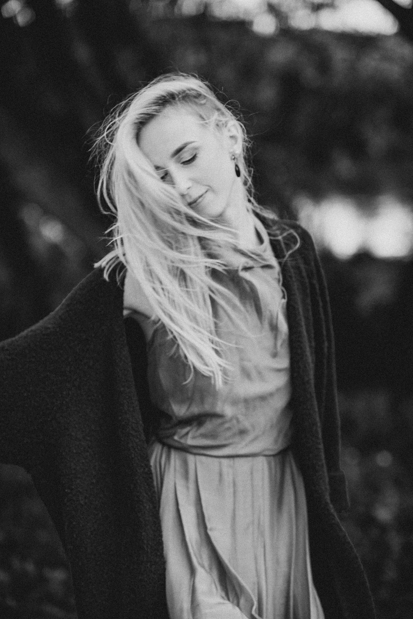 Dramatic black and white portrait with flowing hair against dark background.