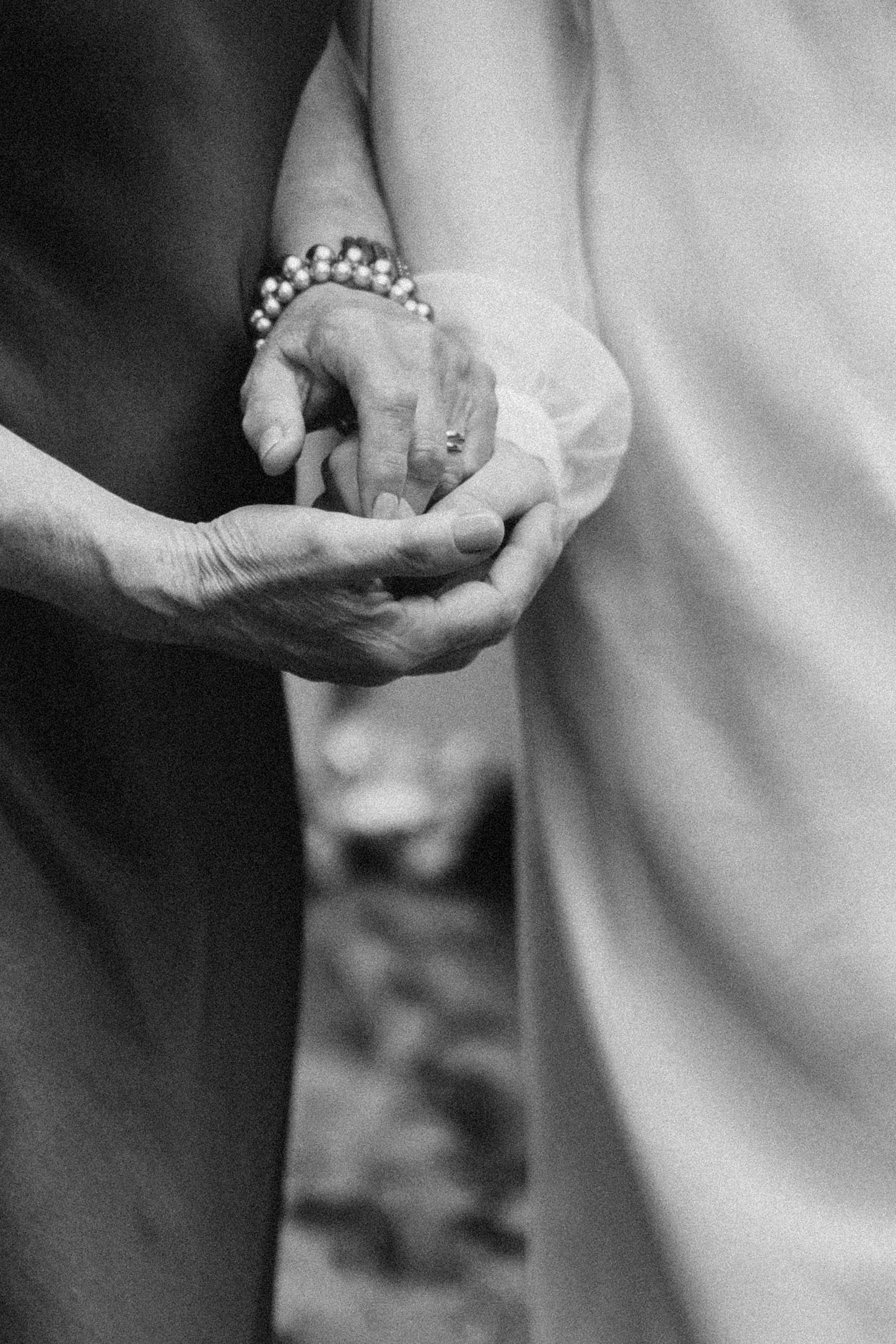 A close-up series of black and white photos showing hands exchanging wedding rings during a ceremony.