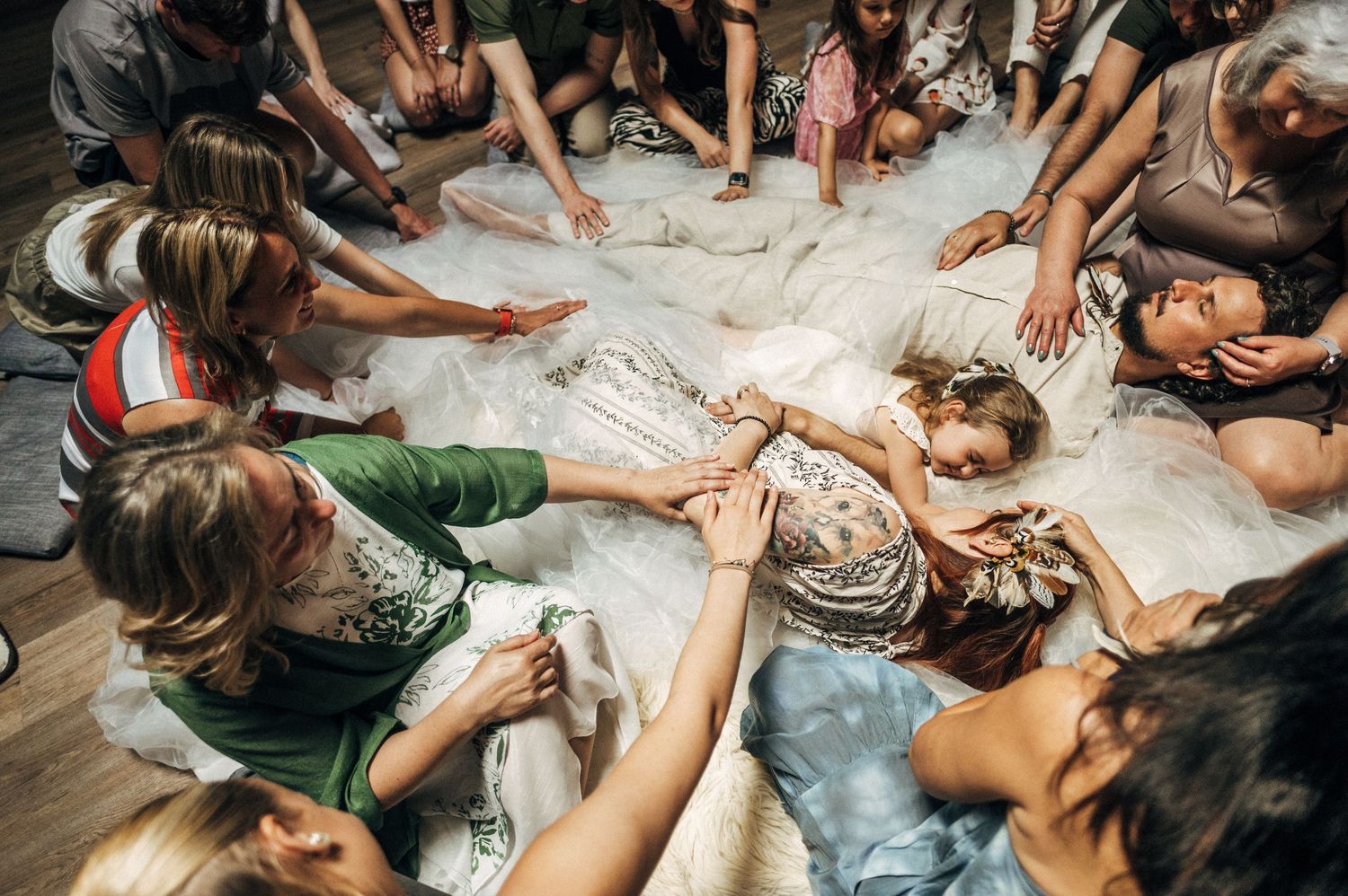 Children lie in circle formation on floor during playful group photo session.