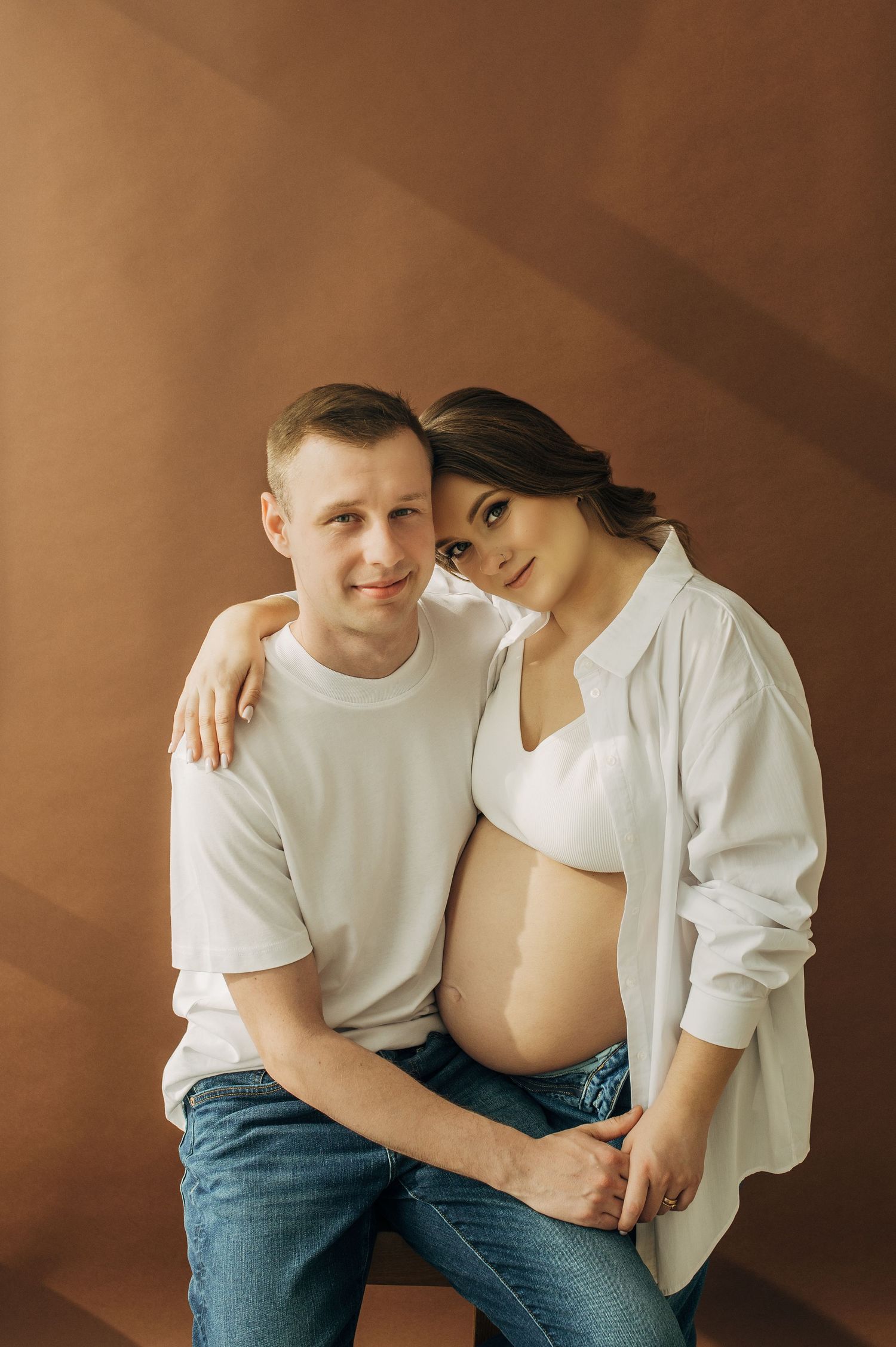 A couple in casual attire shares intimate moments during a photoshoot.