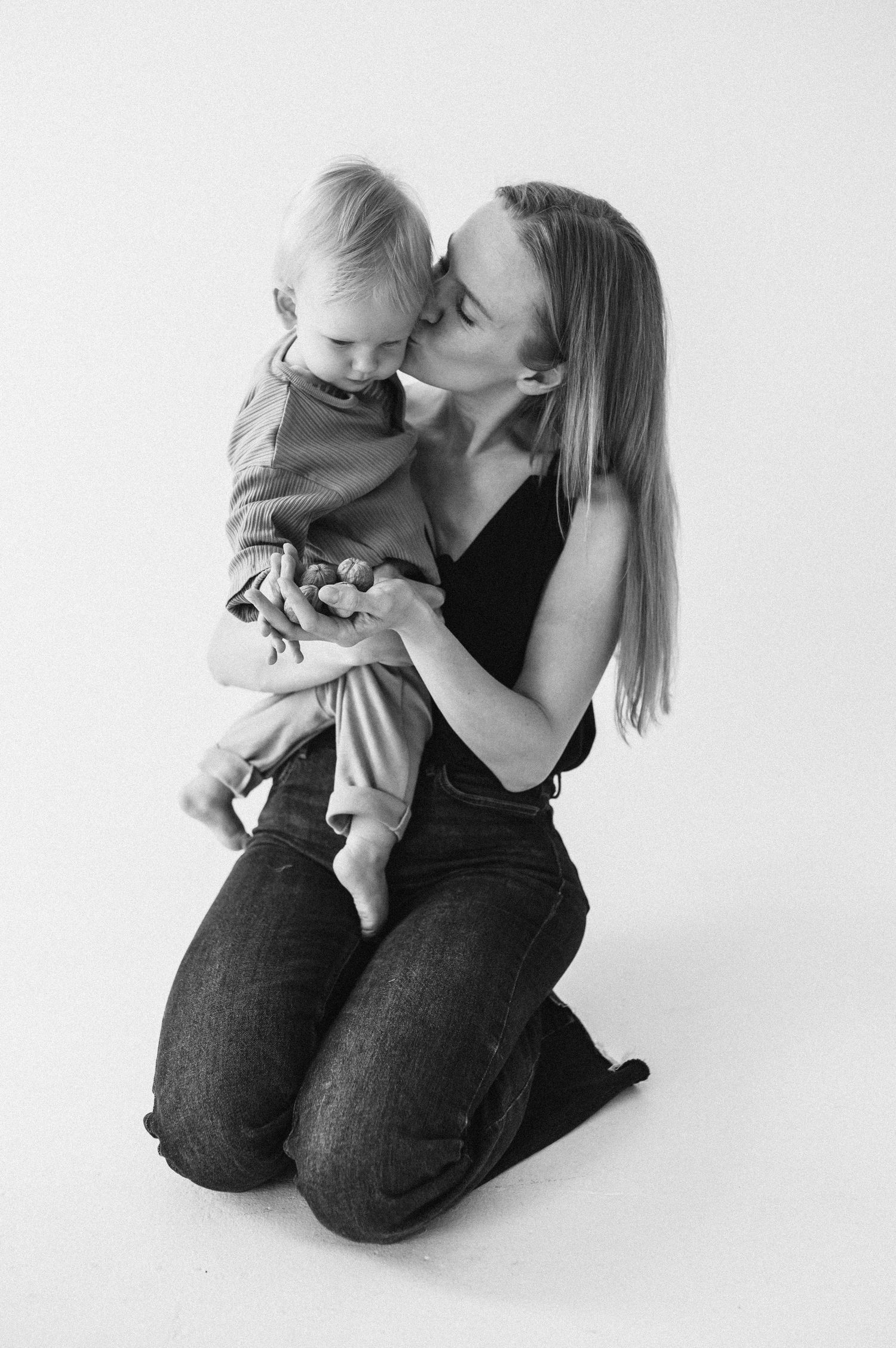 A tender black and white portrait of a parent and child sharing an intimate moment against a white background.
