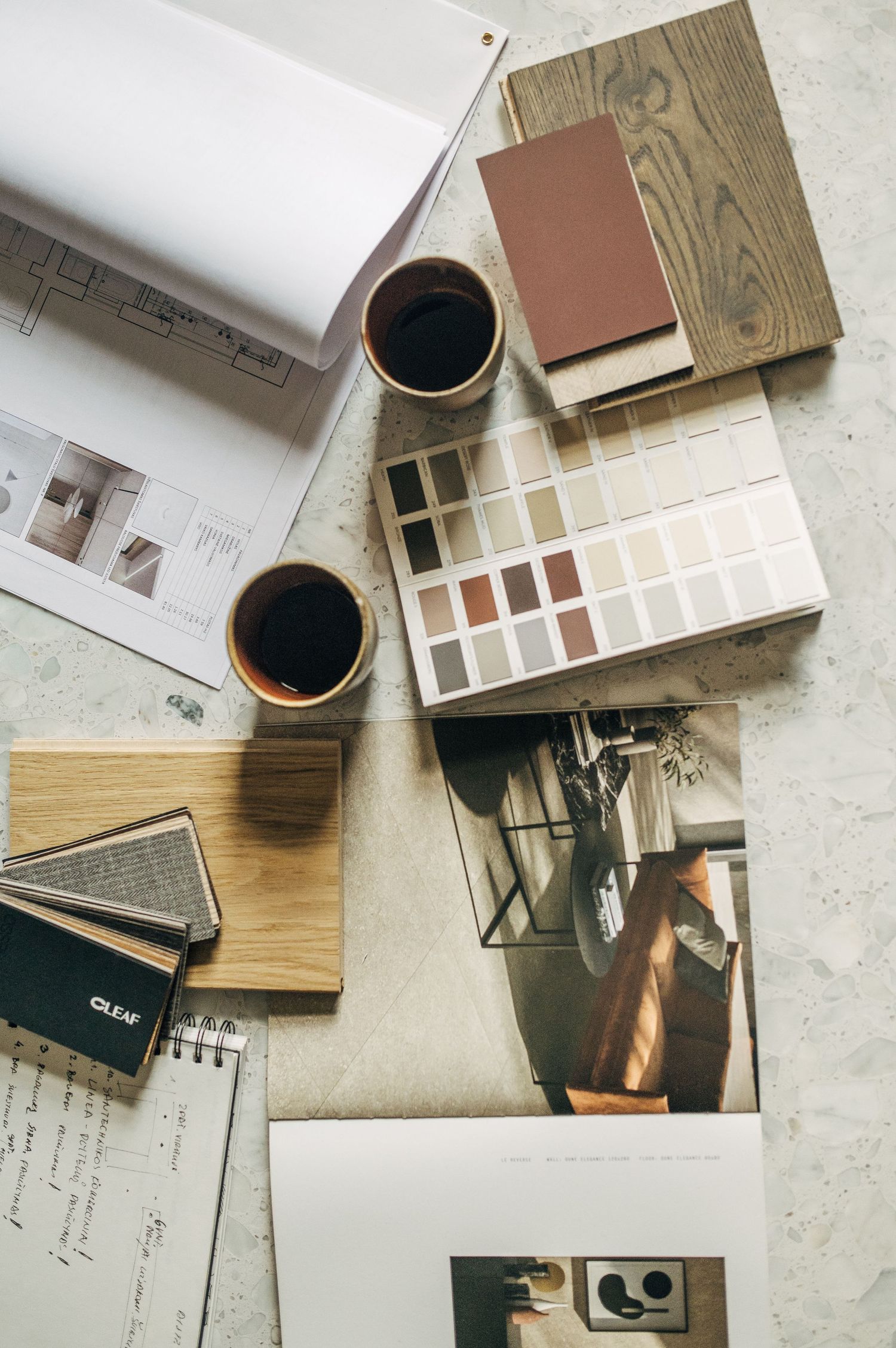 Overhead view of design materials including color swatches and coffee cups on desk.