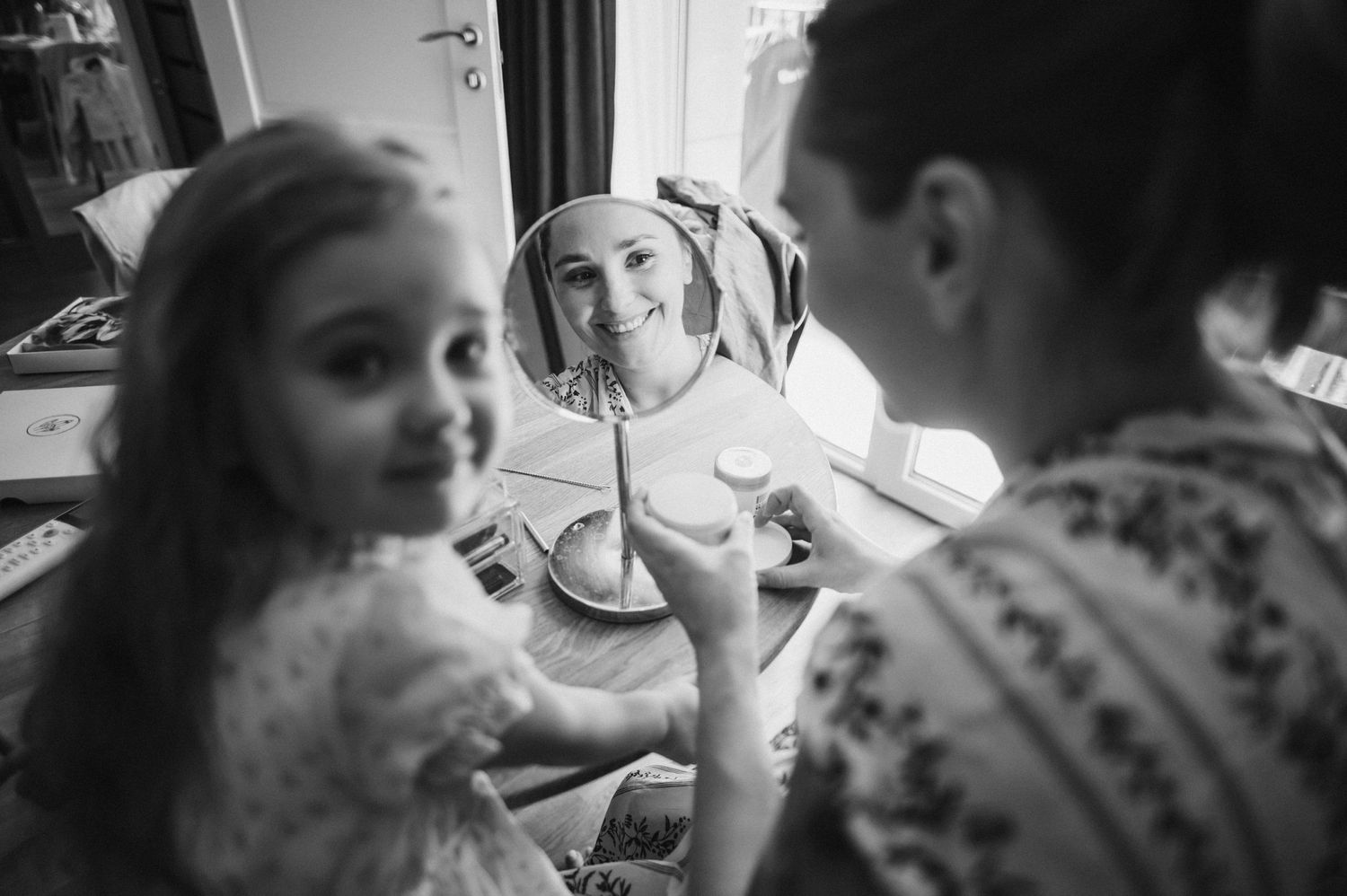 Child looks in mirror during black and white photo session.