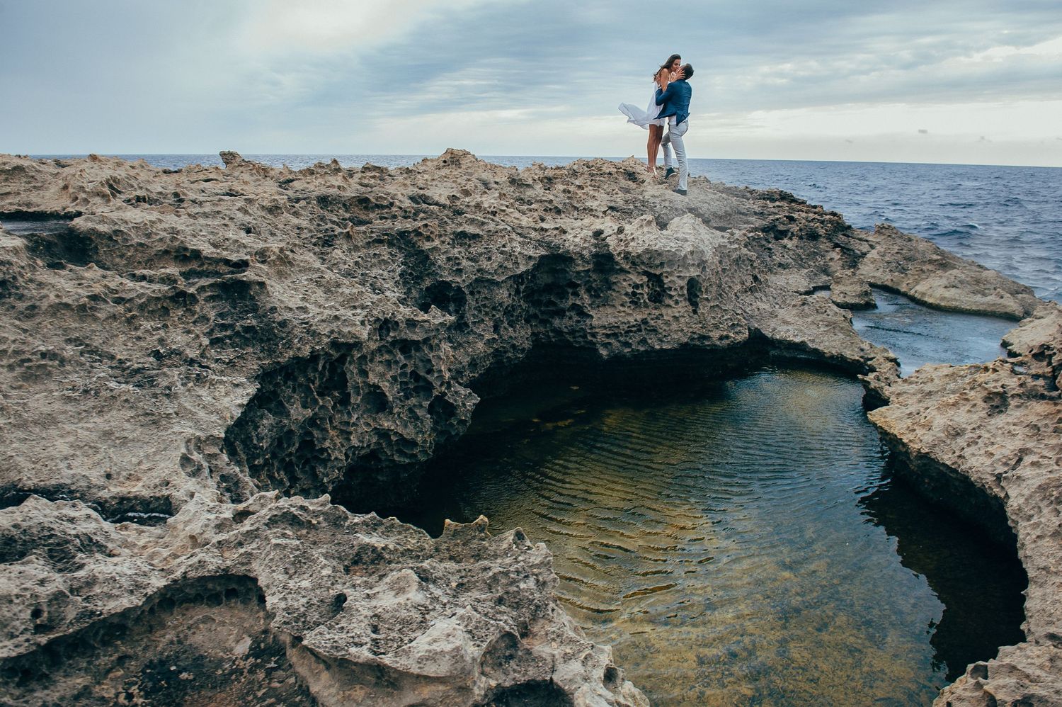 Rocky coastal landscape with crystal clear water and rugged cliffs extending into the ocean.