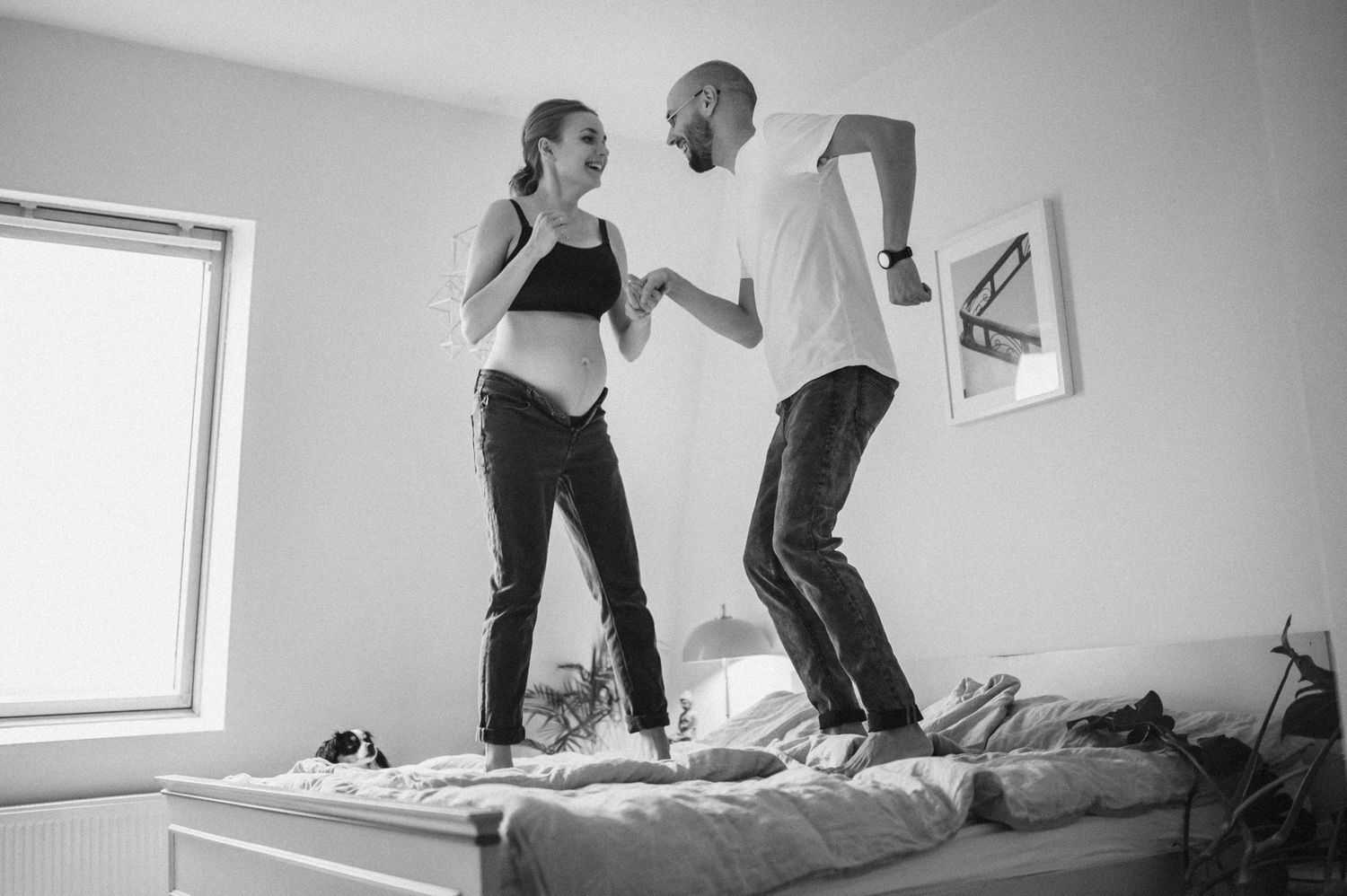 Black and white indoor photography sequence showing playful movement on a bed.