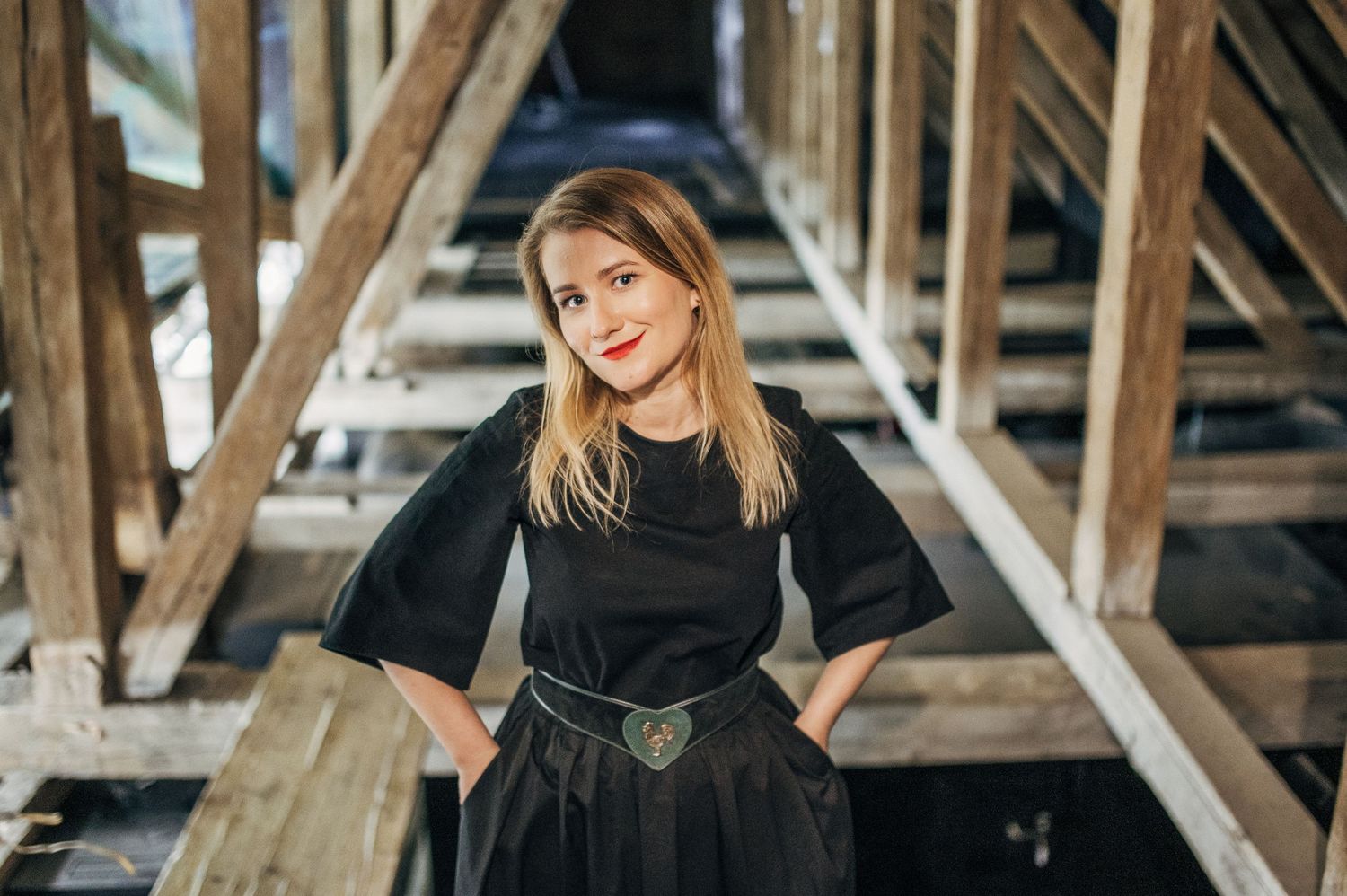 Fashion photography in rustic setting with wooden beams and natural lighting.