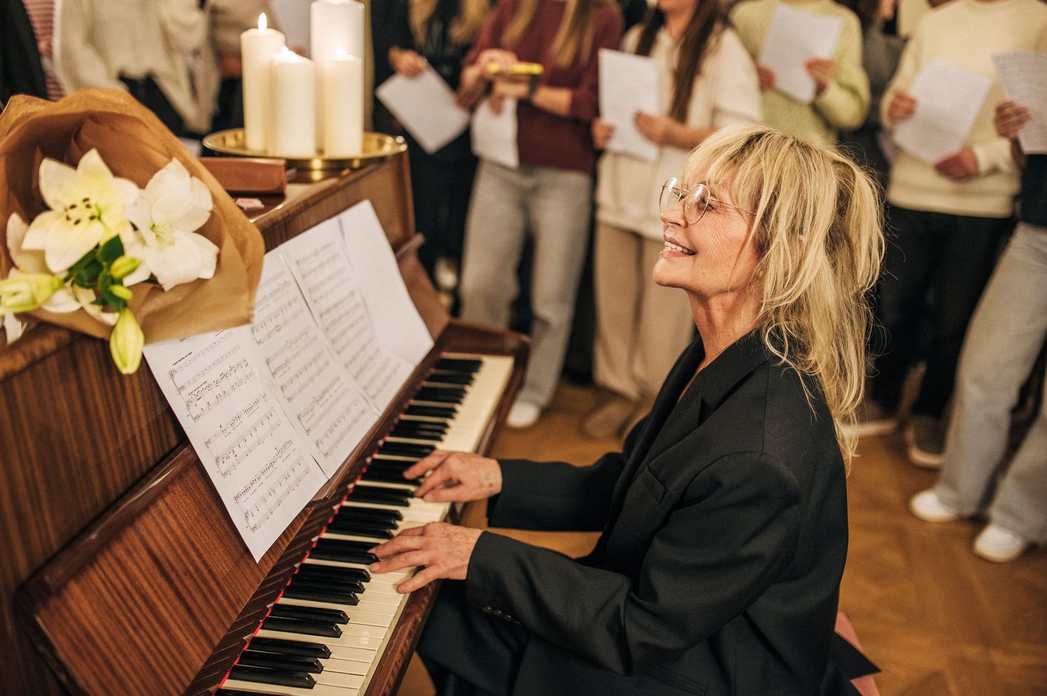 Pianist performs at an event while reading sheet music on a wooden upright piano.