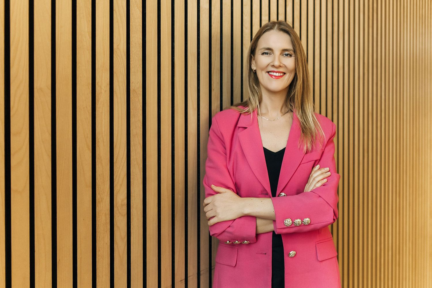Professional headshots of business women in pink blazers standing against a wood paneled wall.