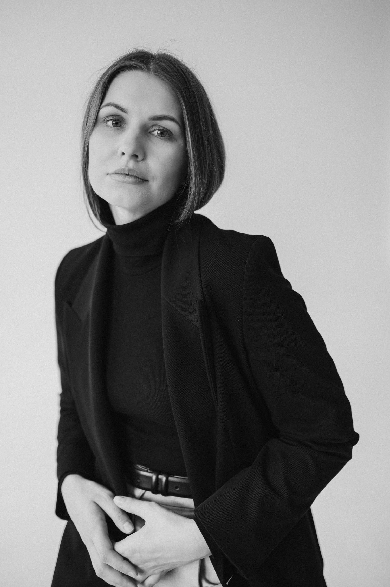 Minimalist black and white fashion portraits featuring model in dark blazer against white background.