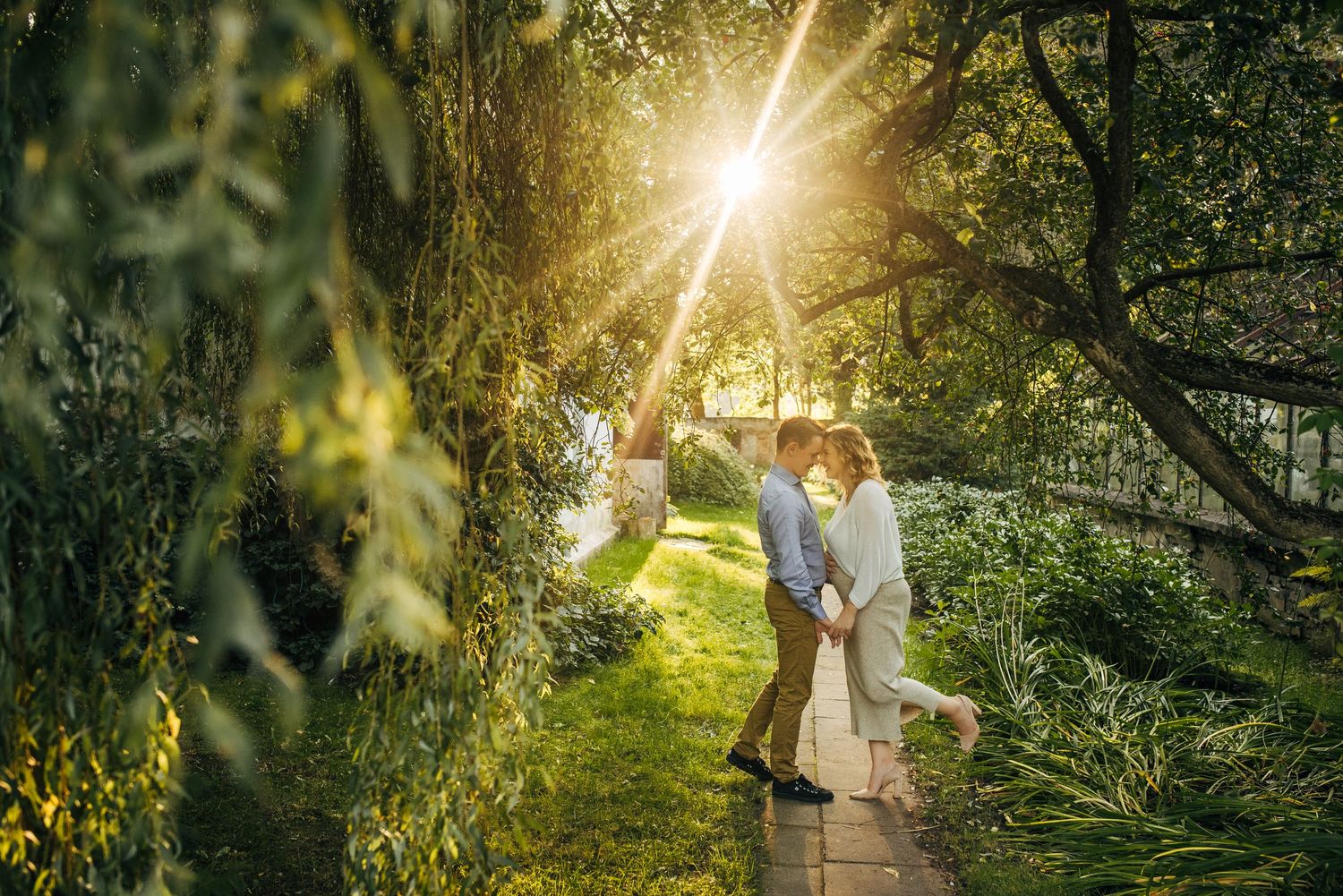 Romantic outdoor photoshoot in sunlit wooded area with golden light filtering through trees.