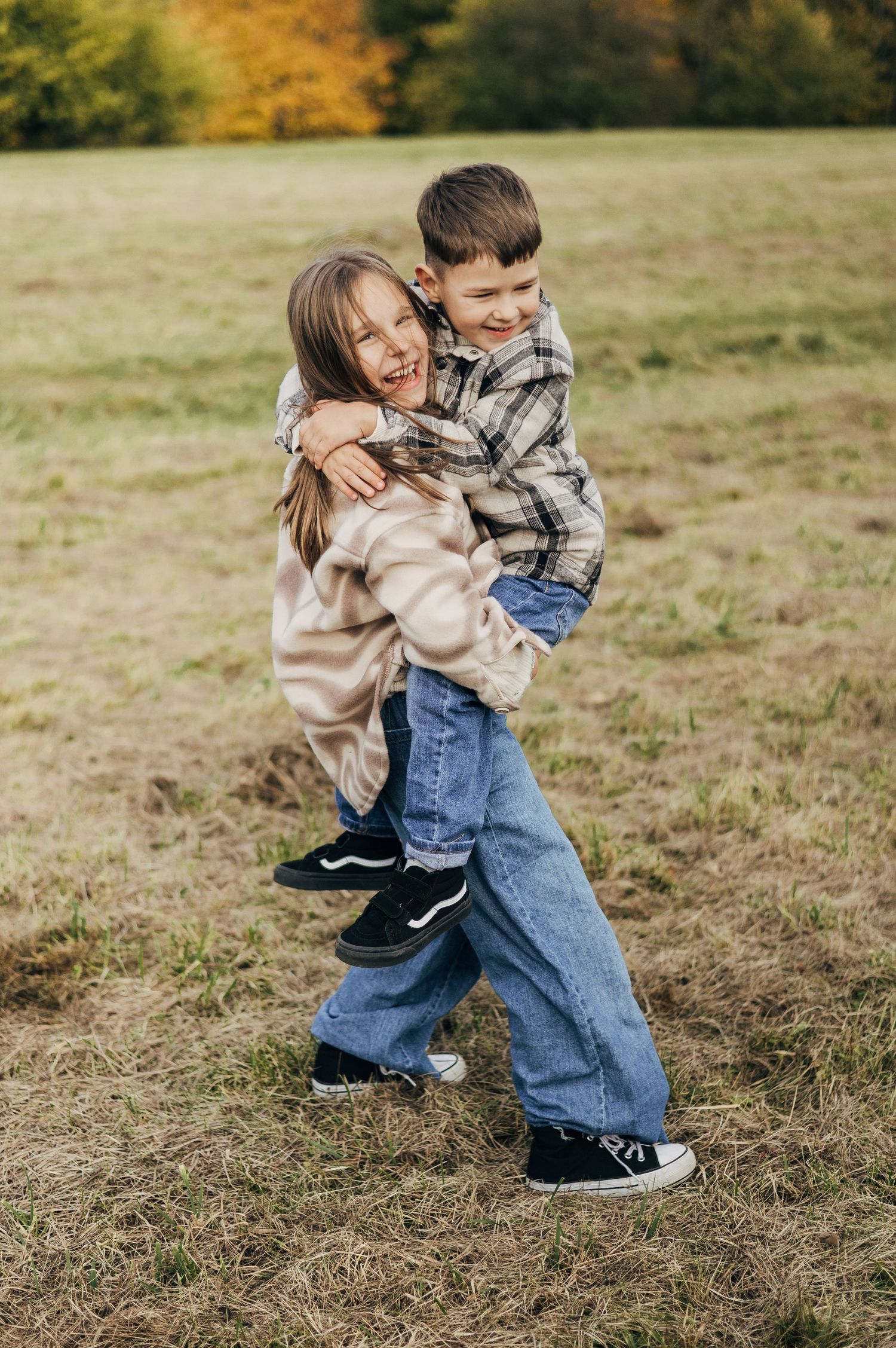 Playful sequence of children running and hugging in a field during autumn.