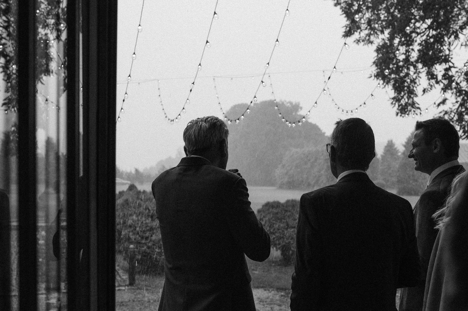 A panoramic black and white shot of a group silhouetted against large windows.