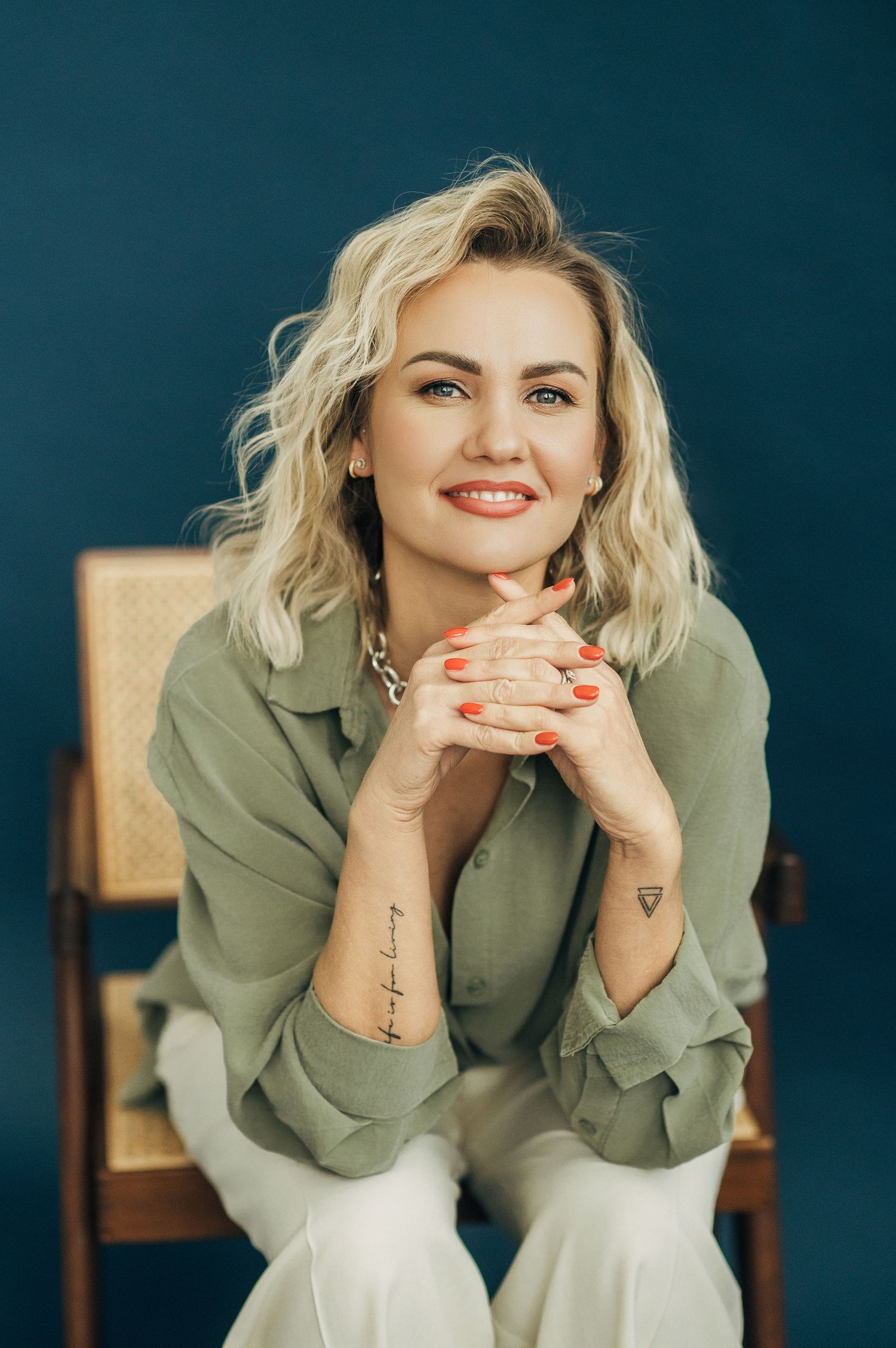Artistic portrait series in sage green shirt against dark blue backdrop.
