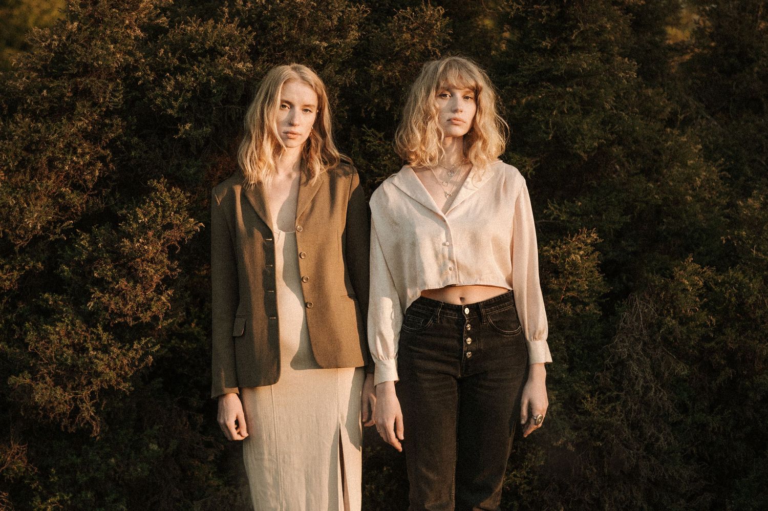 Two people in vintage style clothing pose together against an autumn background.