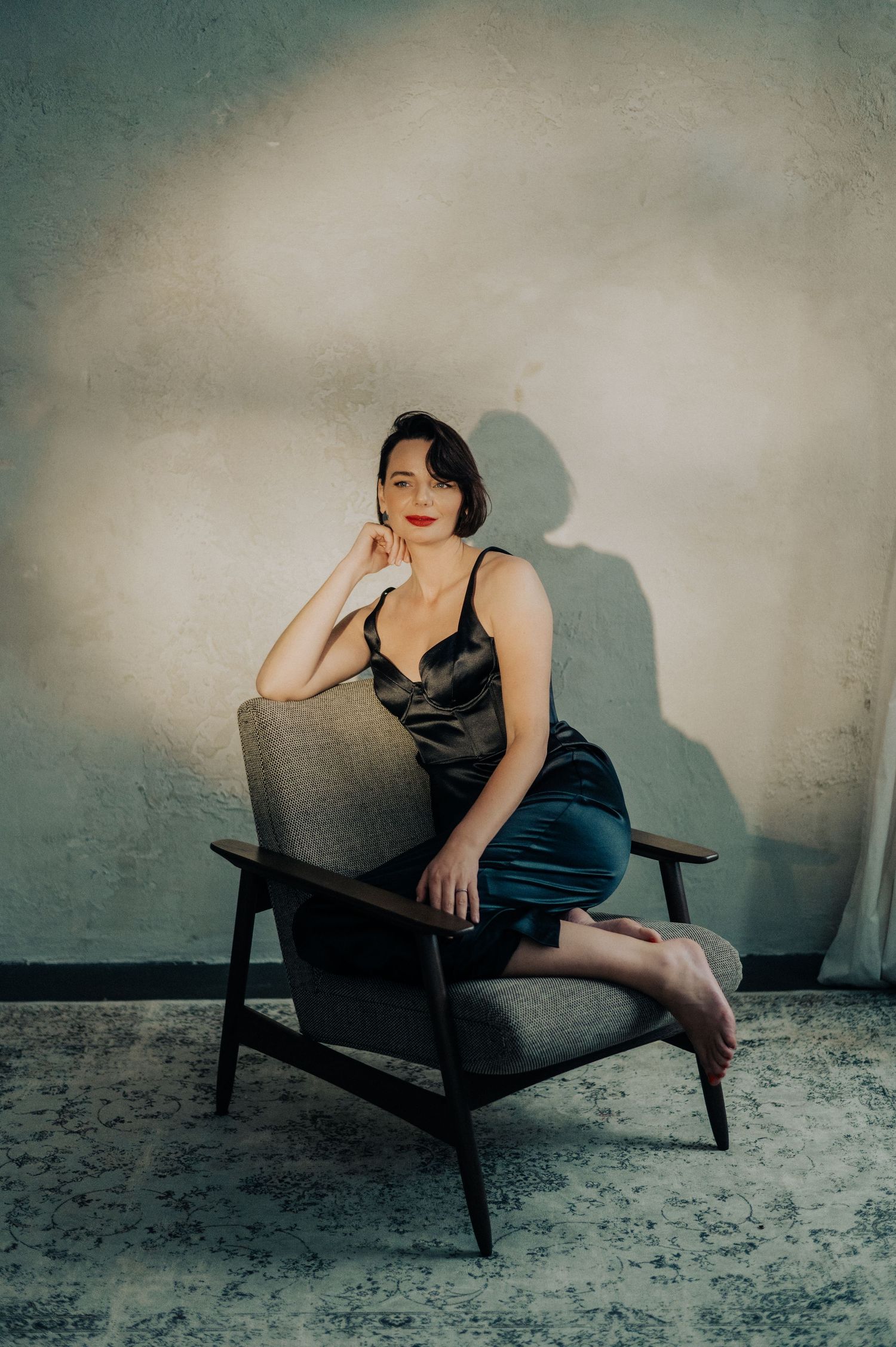 Artistic portraits on vintage chair showing relaxed poses in black dress.