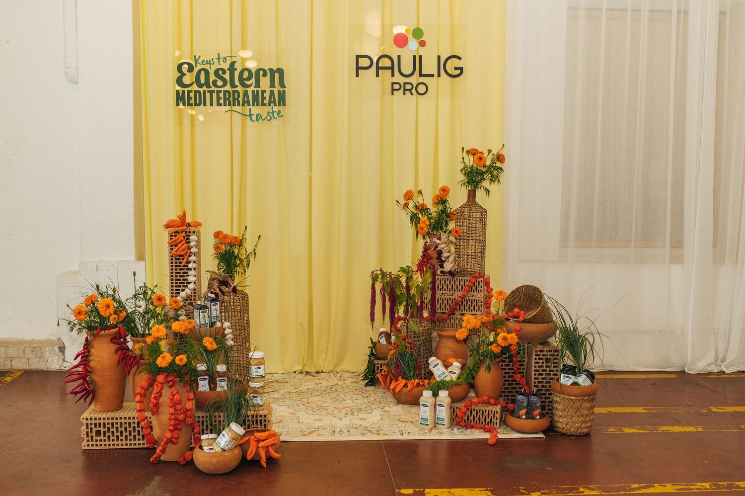 Fall themed photo backdrop with rustic decor, pumpkins, flowers and harvest decorations against a yellow wall.