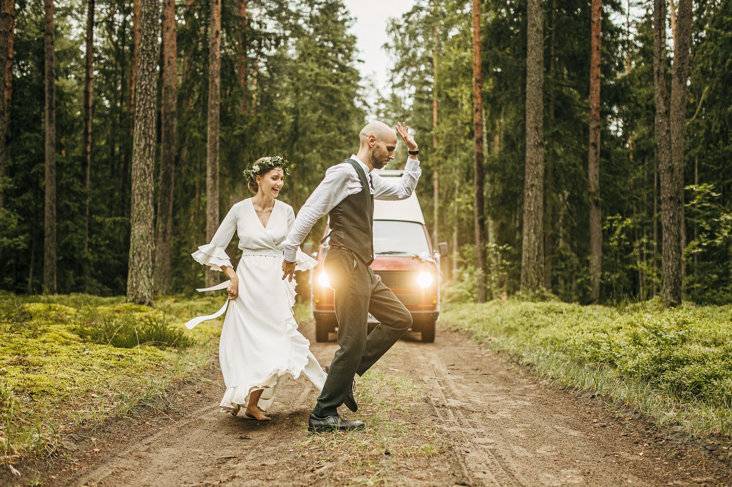 Romantic forest path wedding photos with sunlight filtering through trees.