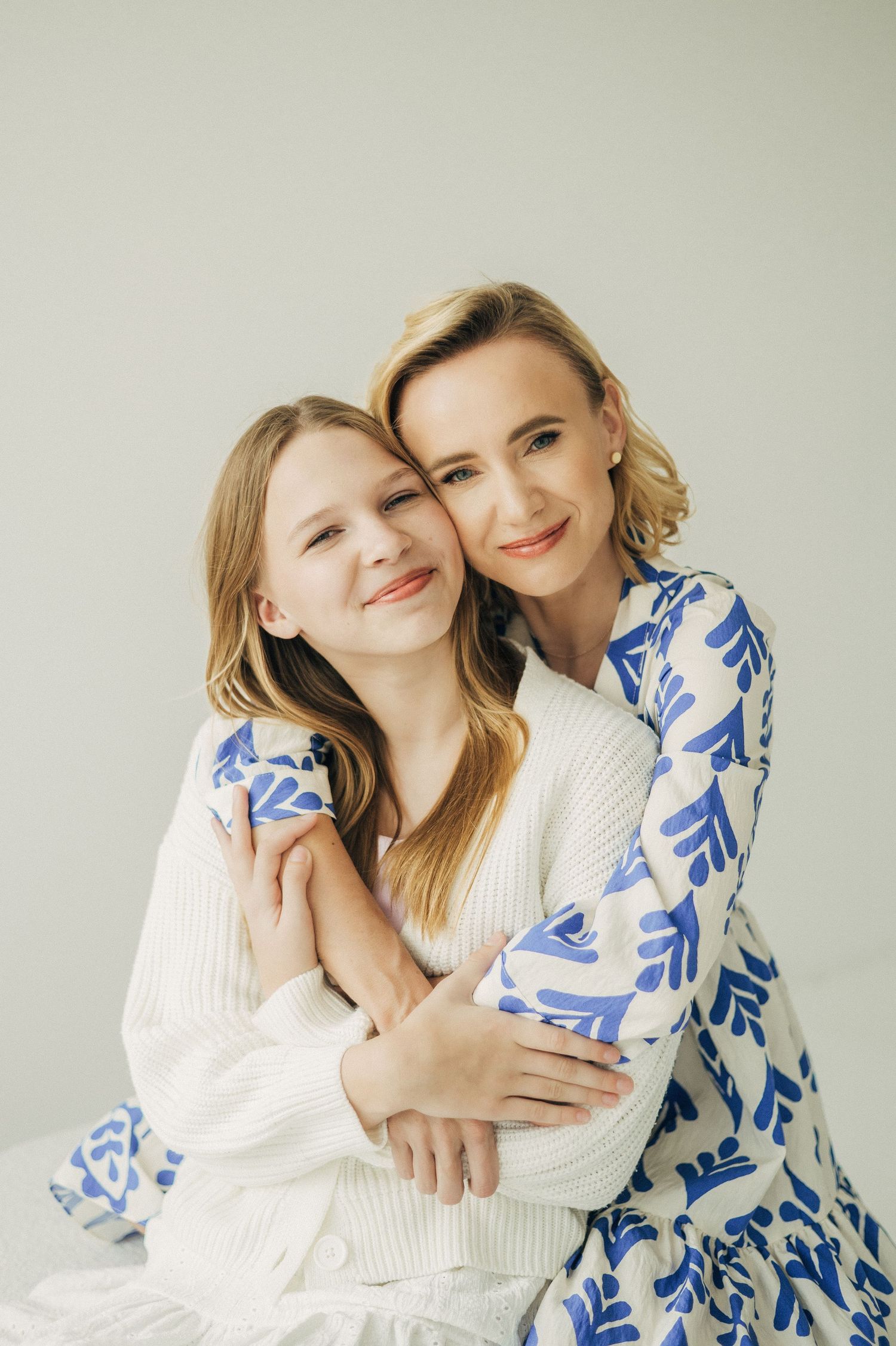 Two people in white and blue outfits share tender moments against a light background.