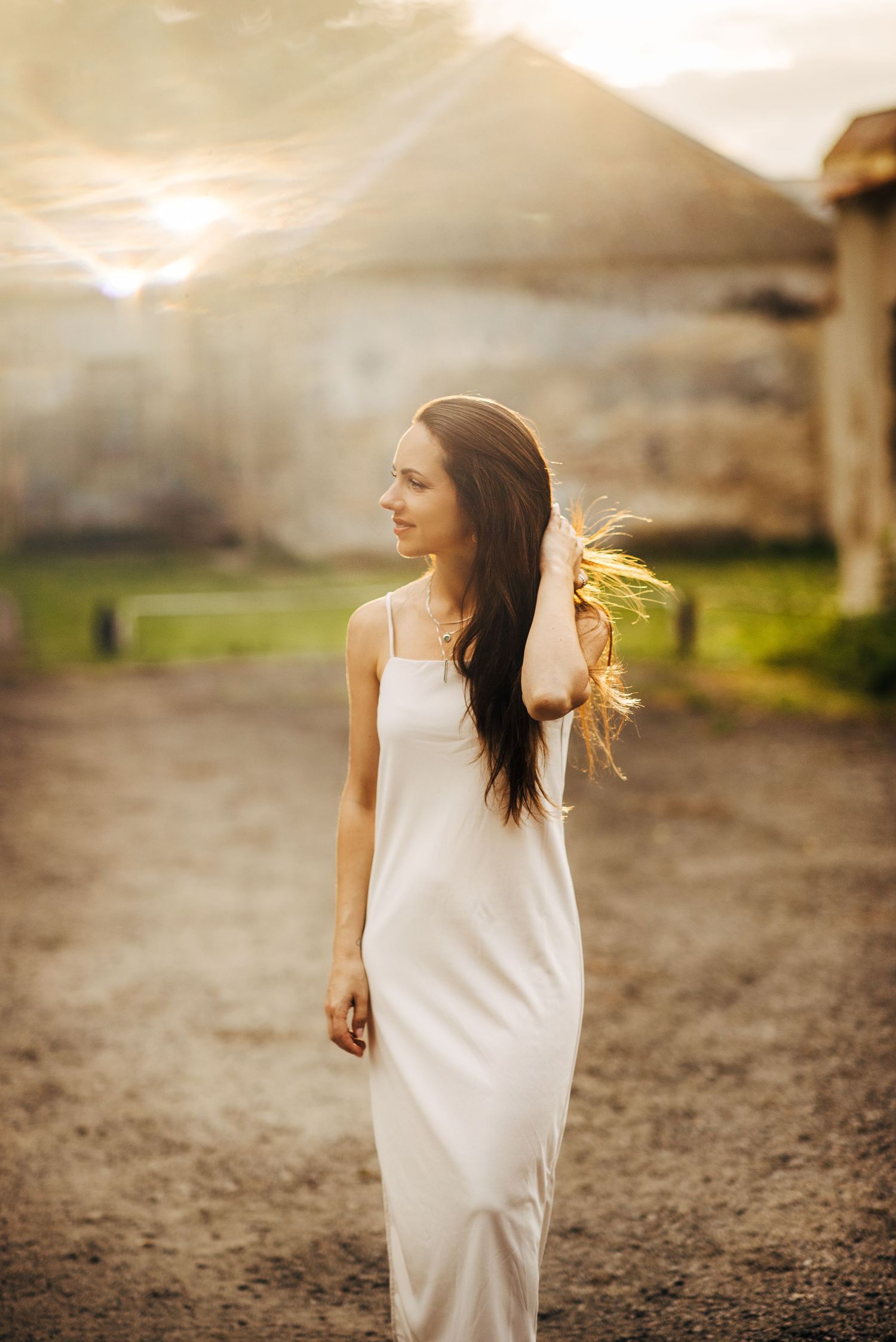 Figure in white dress running through a desert landscape at sunset with hair flowing in the wind.