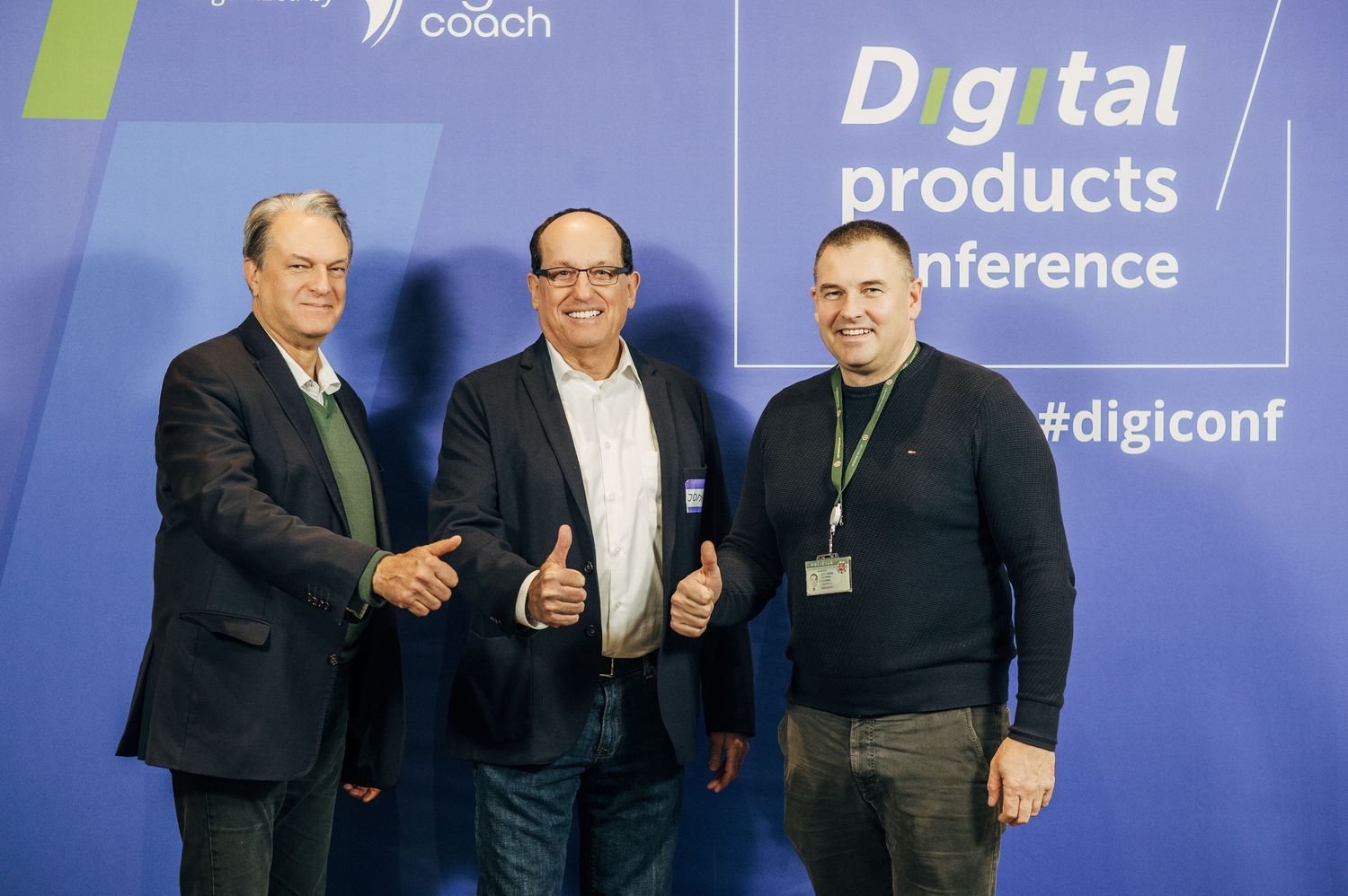 Three men in business attire pose together at a digital products conference with blue backdrop displaying 'digiconf'.