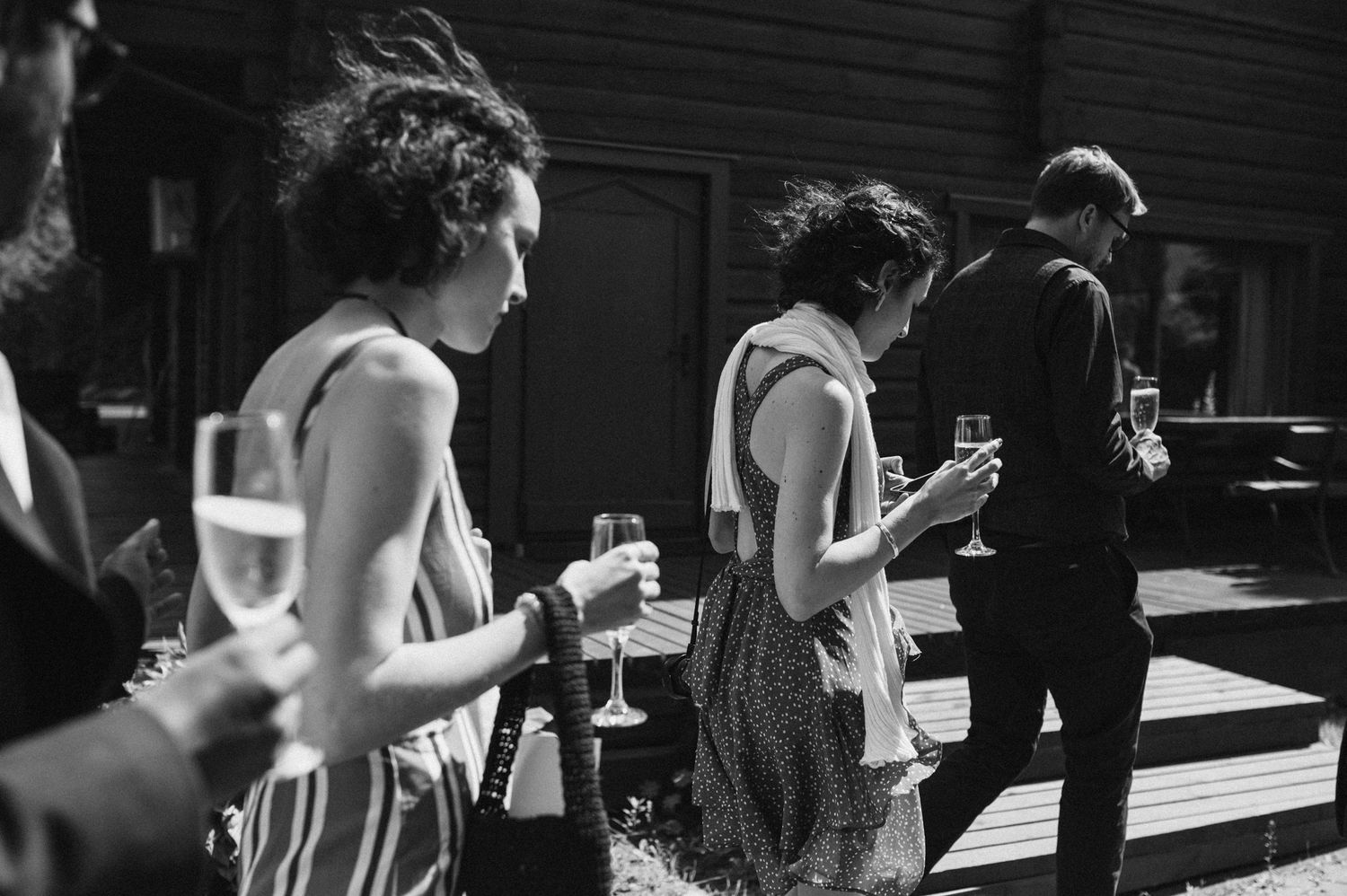 Wedding guests holding drinks at an outdoor reception in the afternoon.