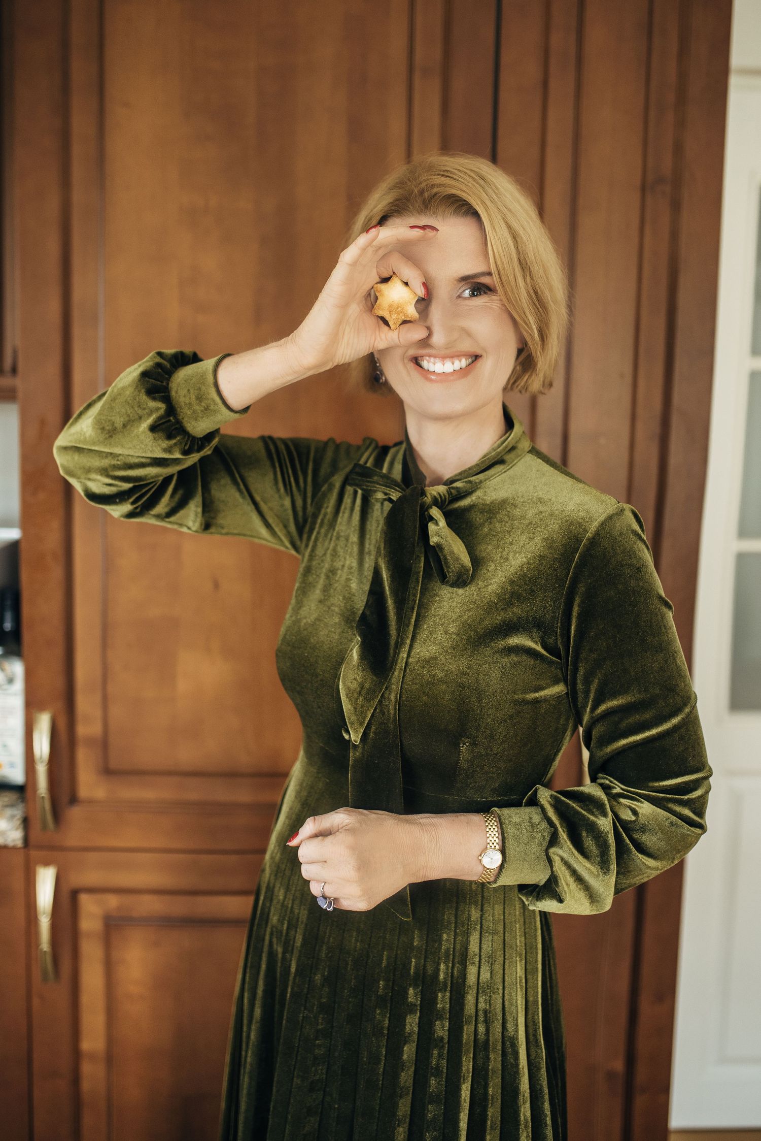 Person in olive green velvet dress enjoying snacks with playful expressions.