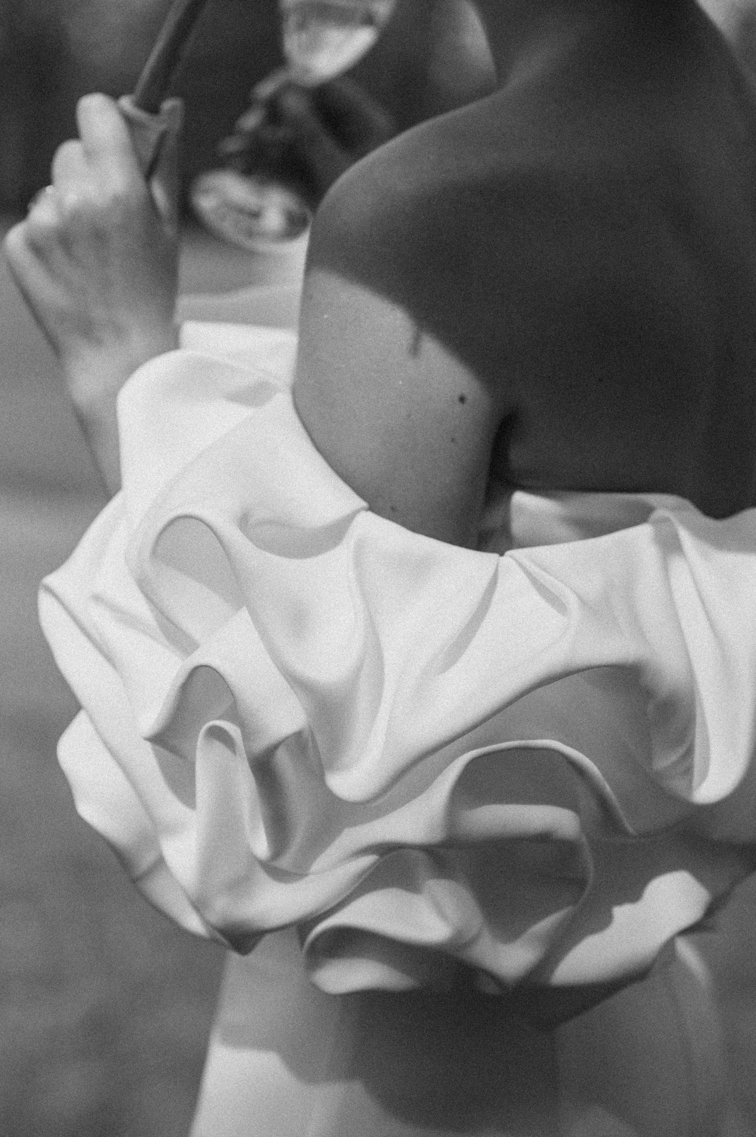 Delicate white ruffled fabric details in elegant black and white photography.