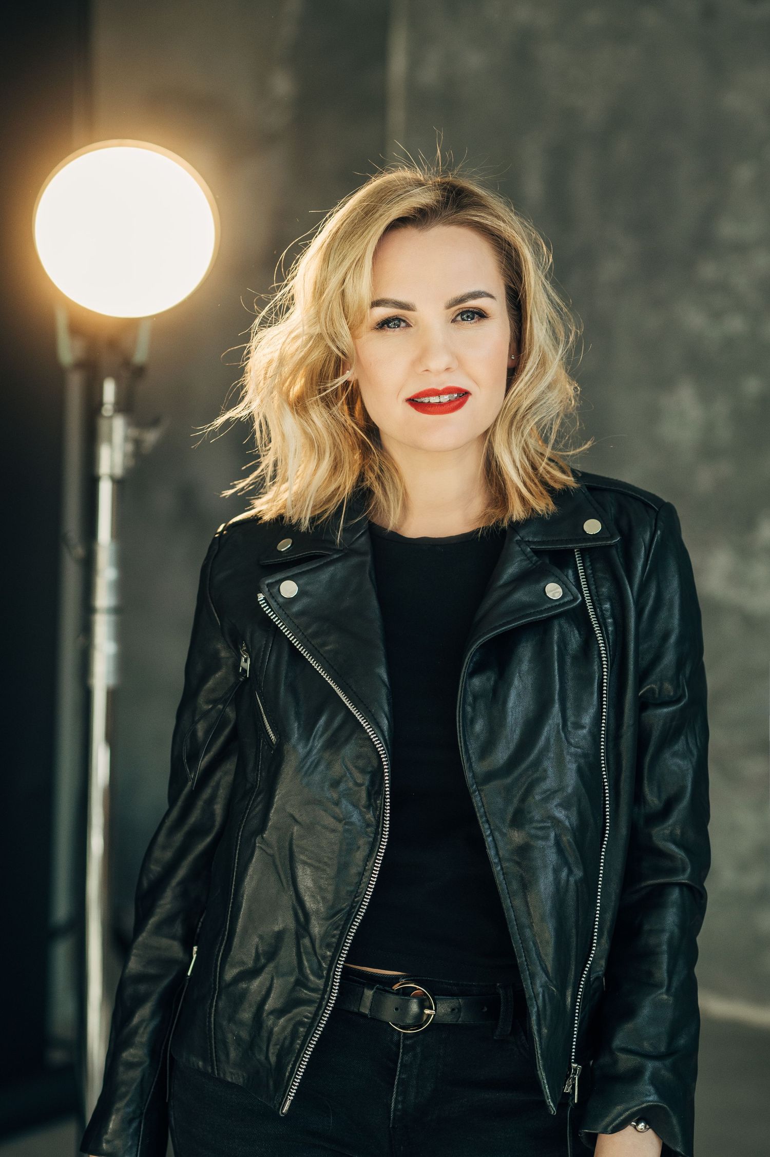 Fashion series featuring black leather jacket against industrial backdrop with dramatic lighting.