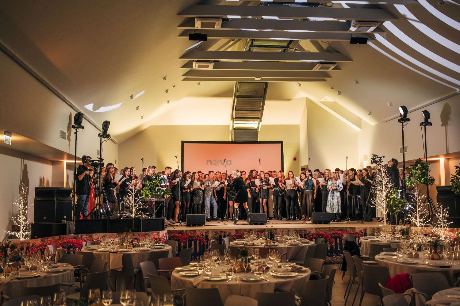 A panoramic view of a large banquet hall setup with round tables and dramatic lighting for a formal event.