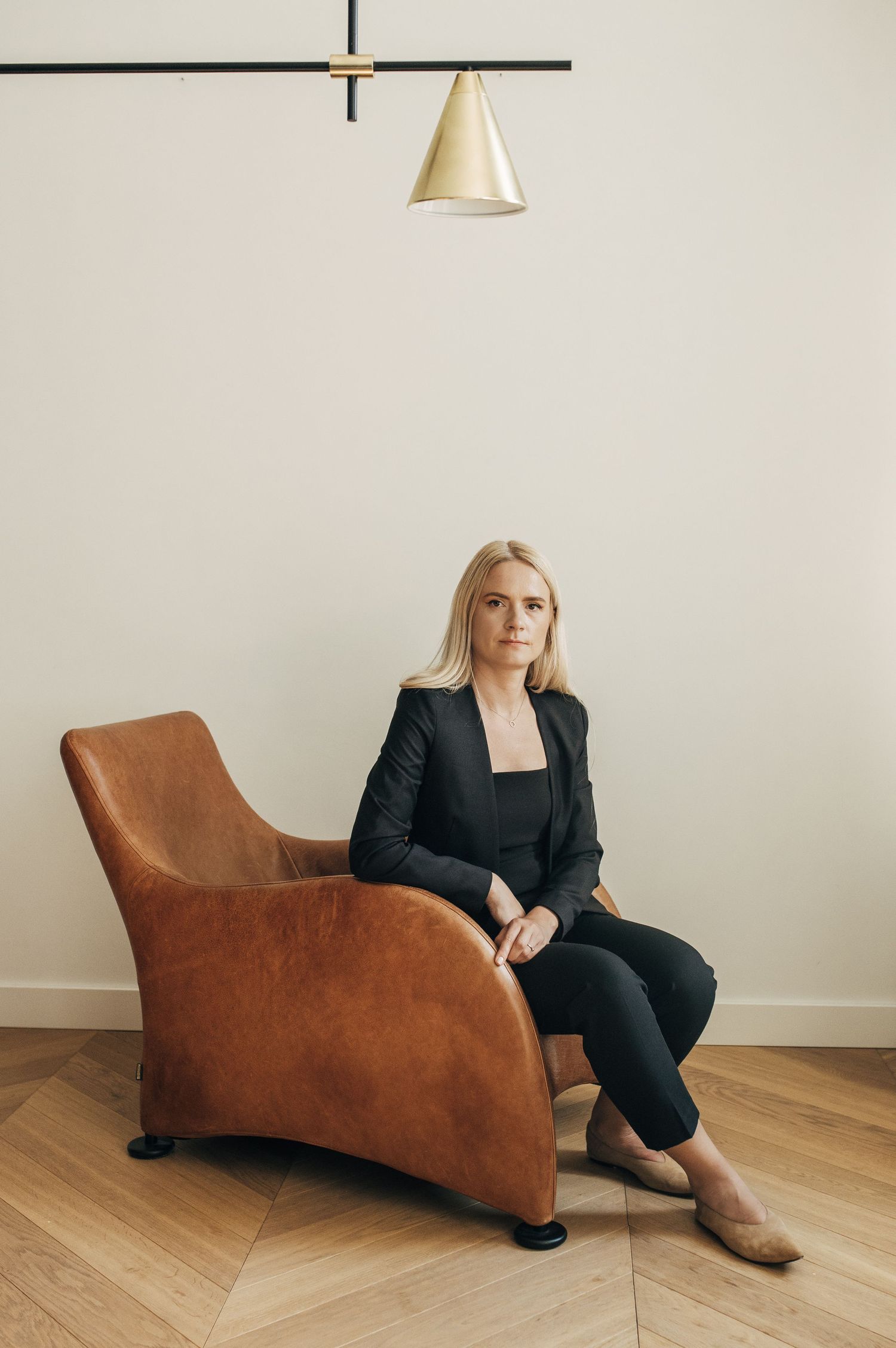 Elegant business portrait series with brown leather furniture and minimalist decor.