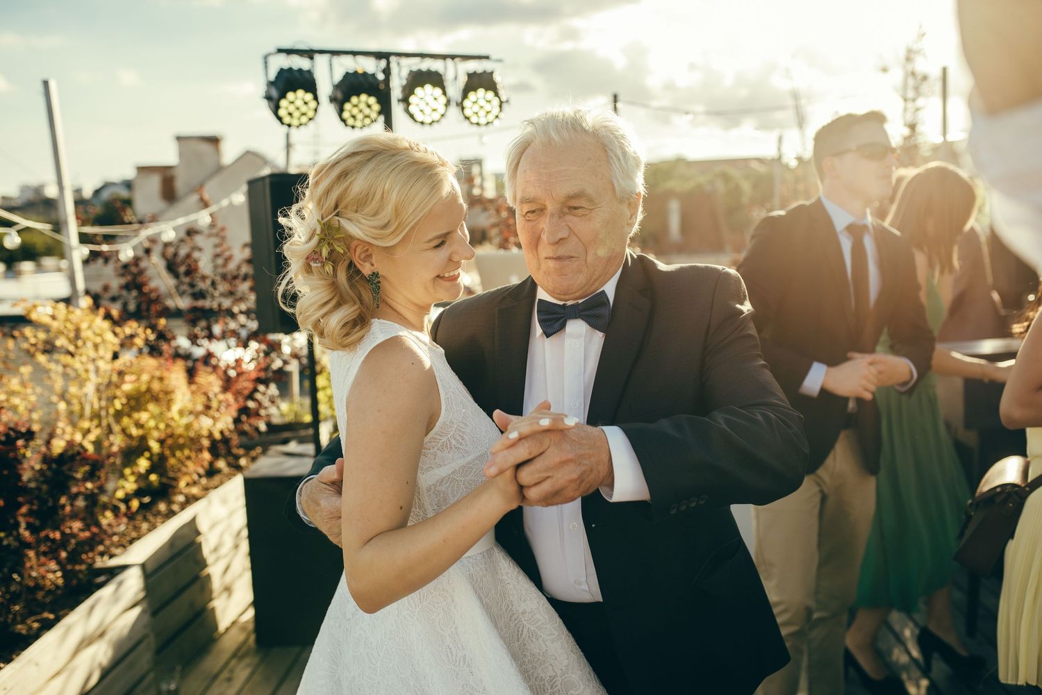 Wedding celebration outdoors with guests mingling during golden hour sunset.