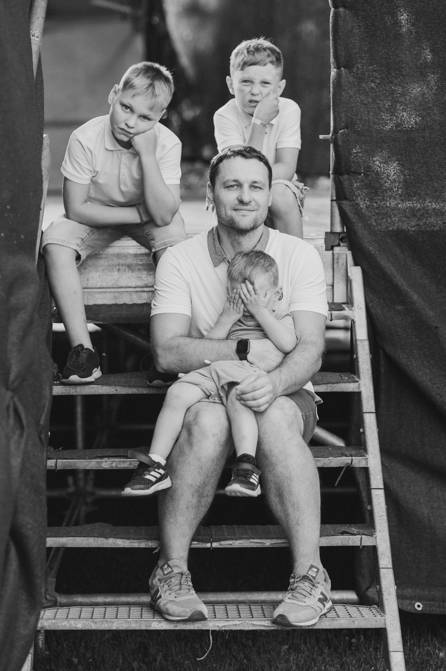 Family portrait session on rustic wooden steps shows tender moments between loved ones.