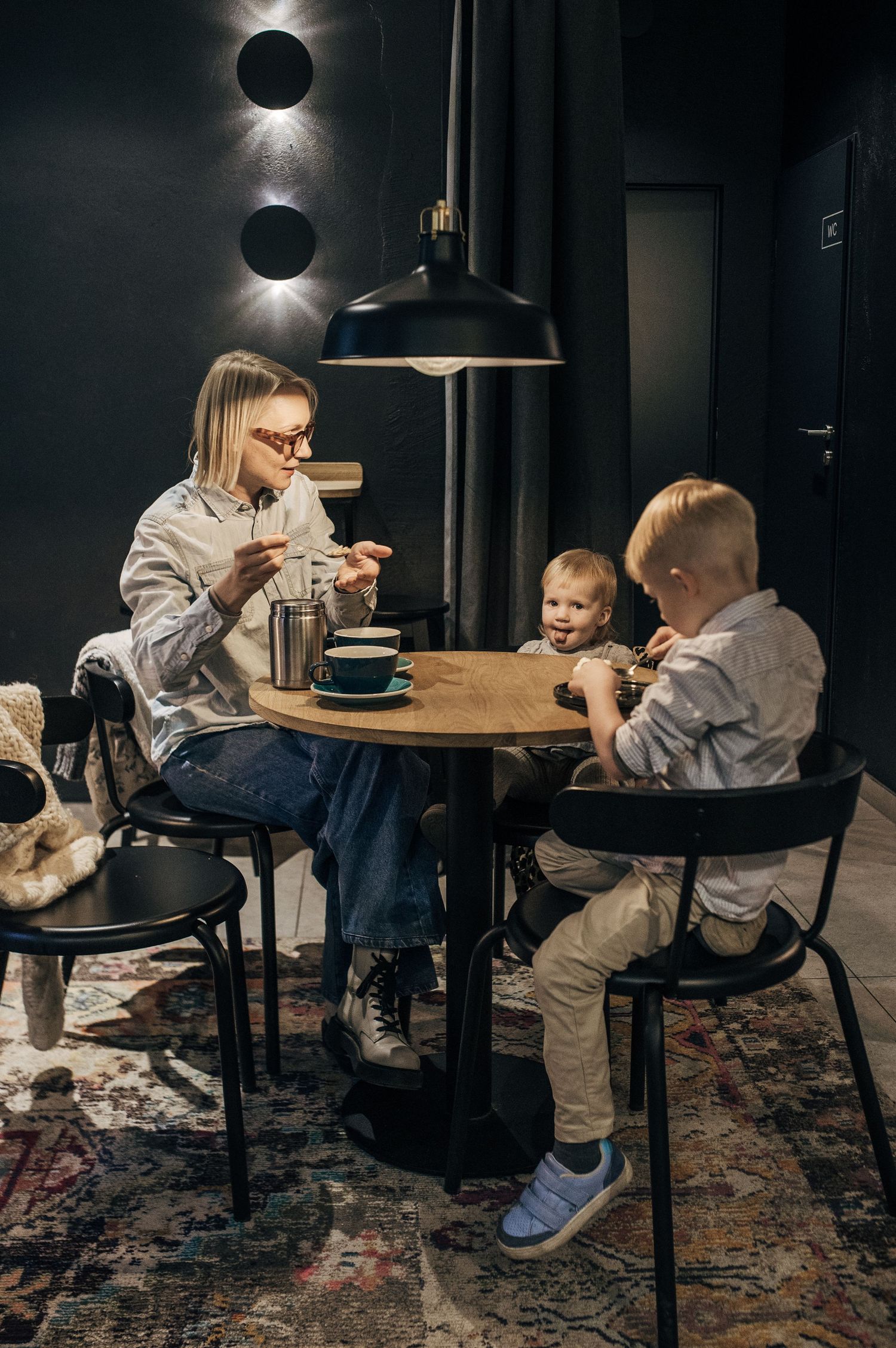 Indoor lifestyle sequence showing parent and child sharing a meal at a wooden table under moody lighting.