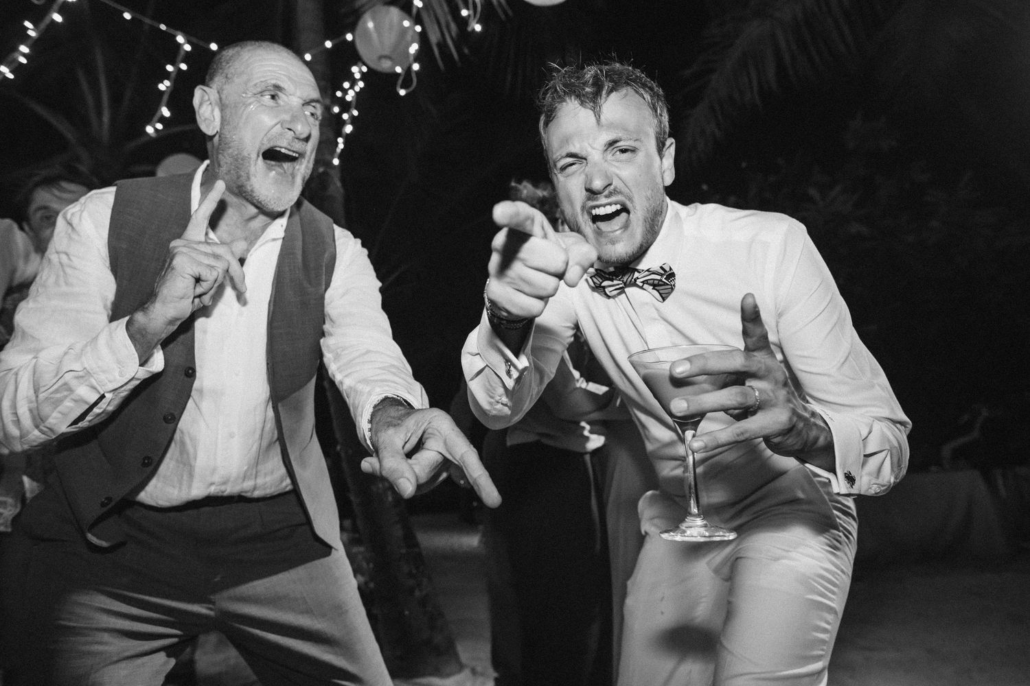 Wedding guests laughing and dancing together during an energetic reception celebration.