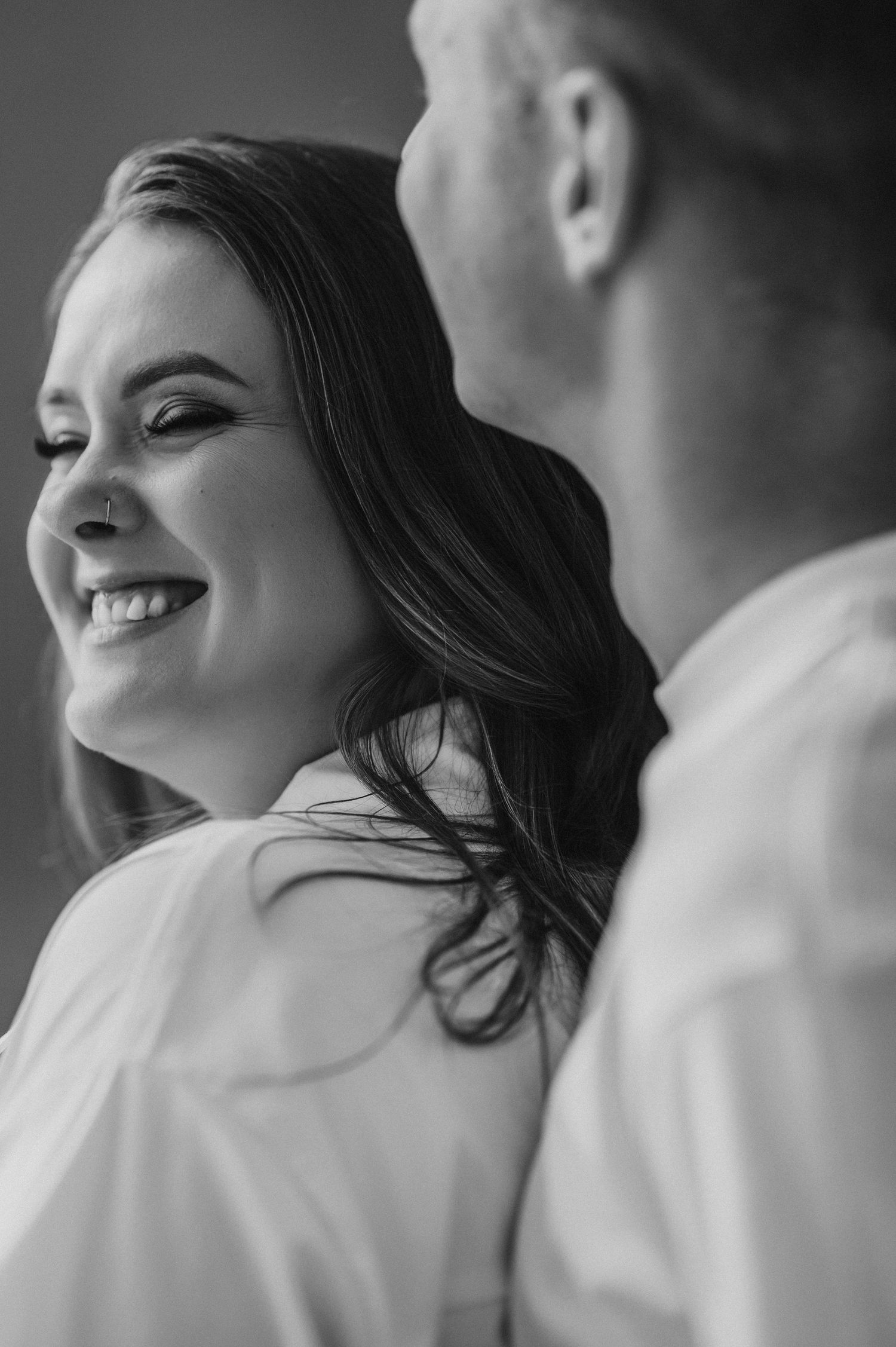 Black and white portrait of couple sharing intimate moment during pregnancy photoshoot.