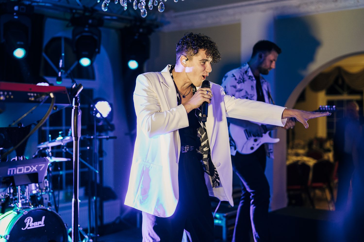 A live band performs on stage with blue lighting and musical equipment during an evening entertainment event.