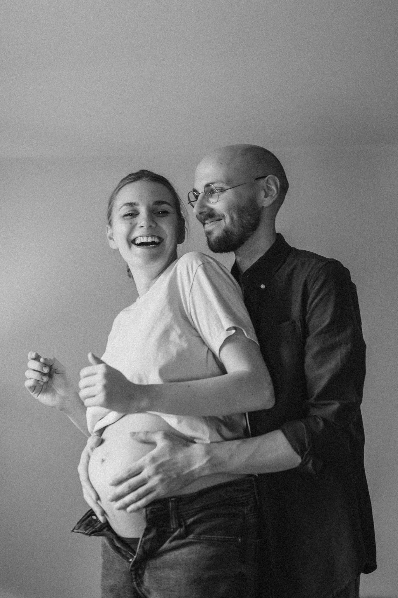 Series of black and white photos showing intimate embraces and joyful laughter in a minimalist setting.