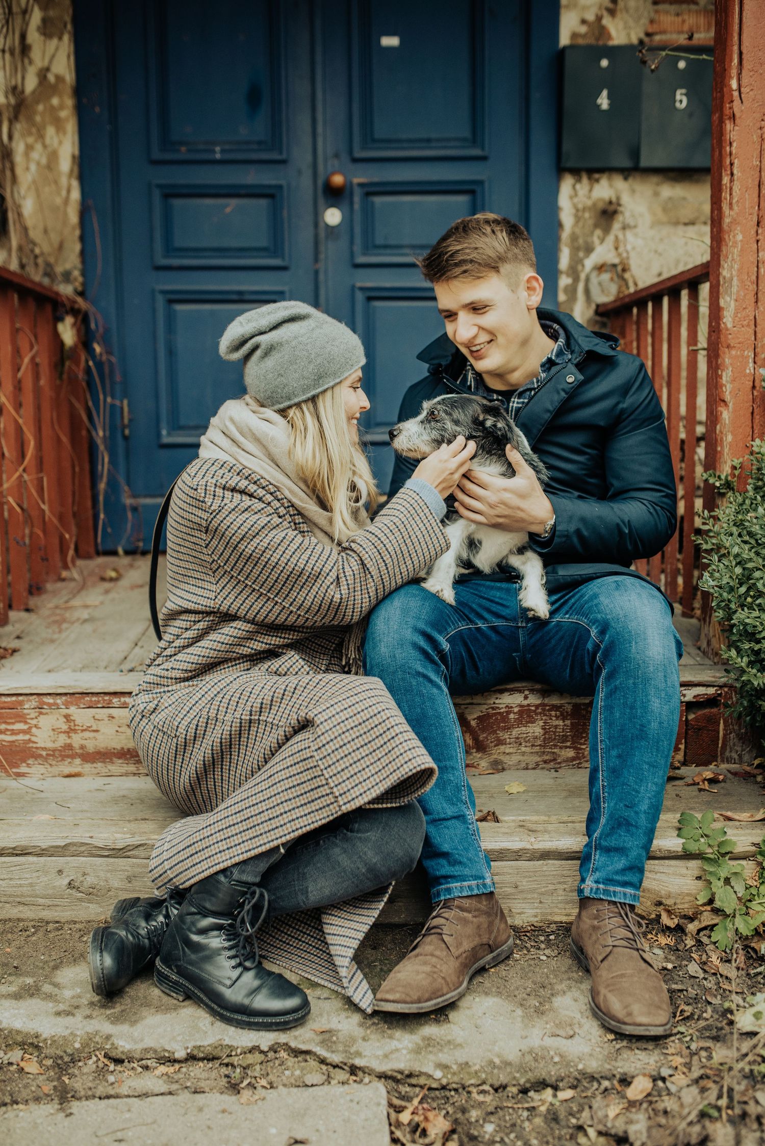 Intimate moment shared on steps with vintage blue doors in background.