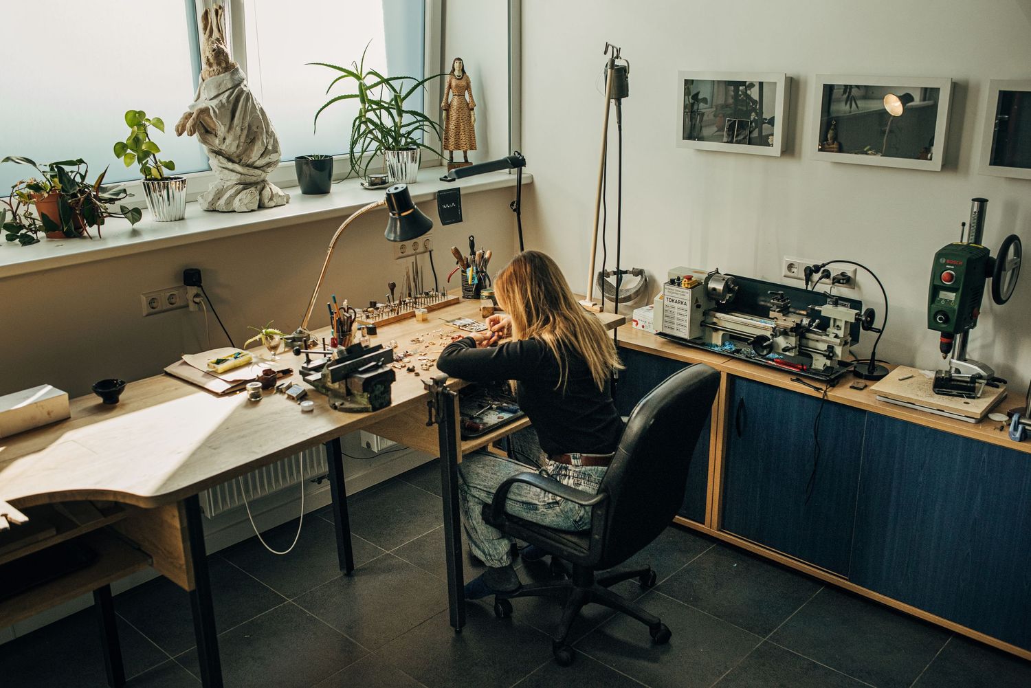 Modern office space with desks, chairs and plants in natural lighting.
