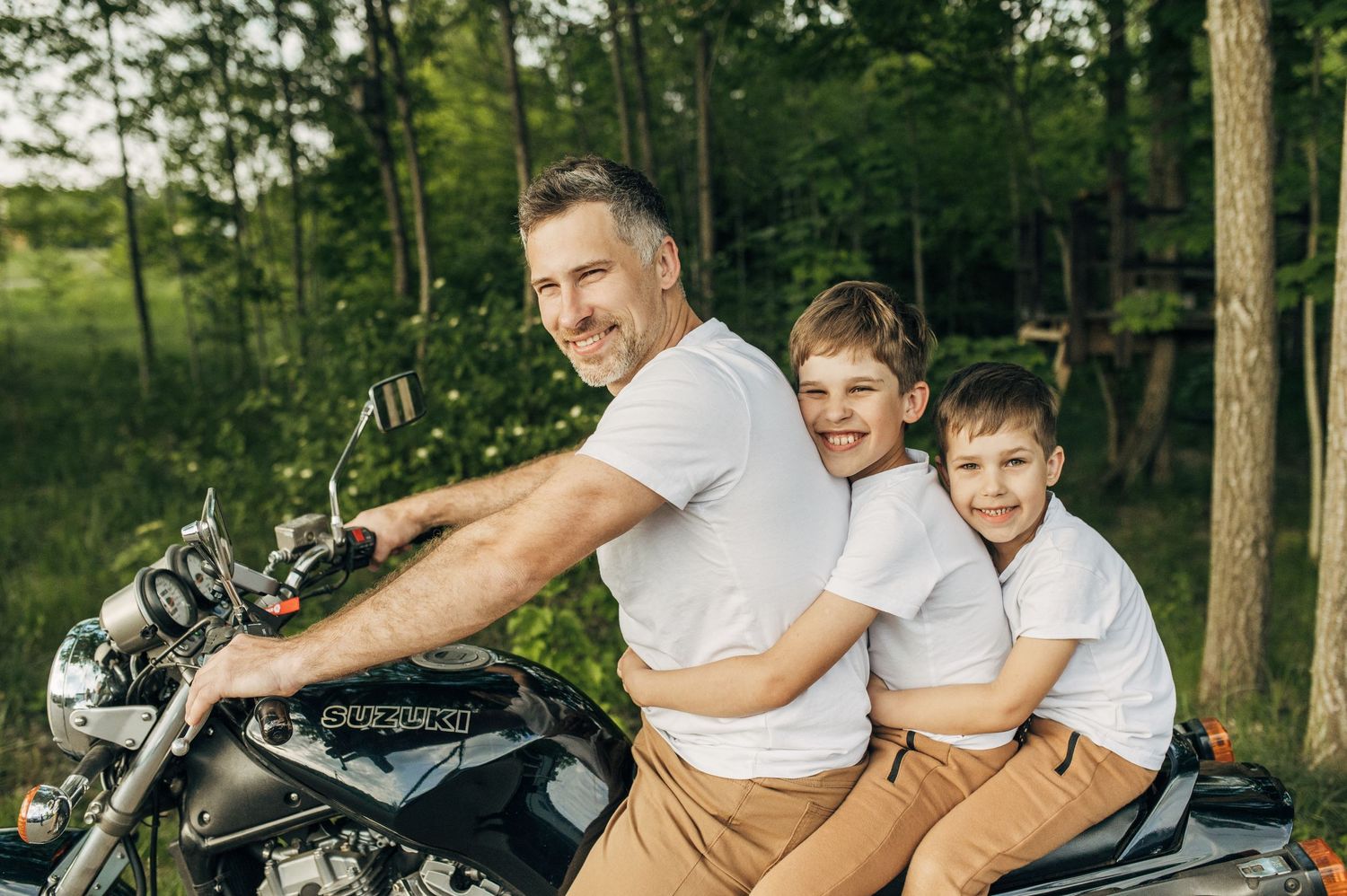 Family enjoying an outdoor motorcycle adventure in a wooded setting.