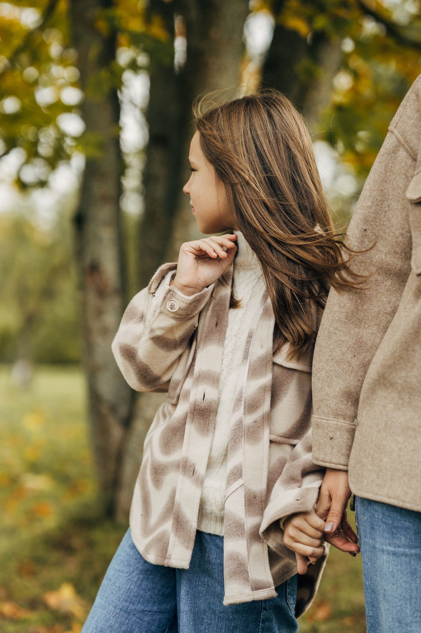 A candid autumn portrait of someone in a beige shirt against fall foliage.