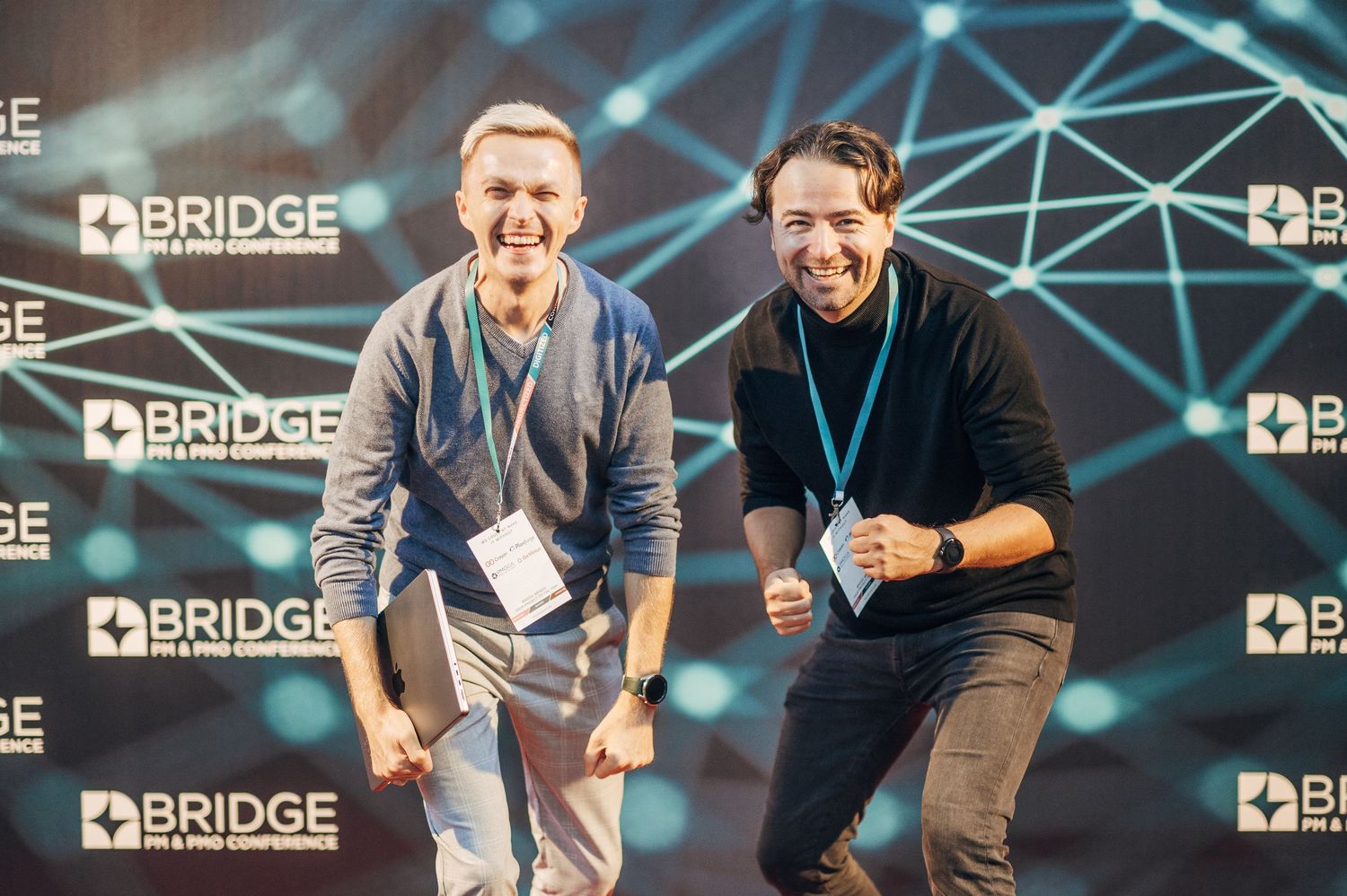 Speakers presenting at Bridge conference with digital network background display.