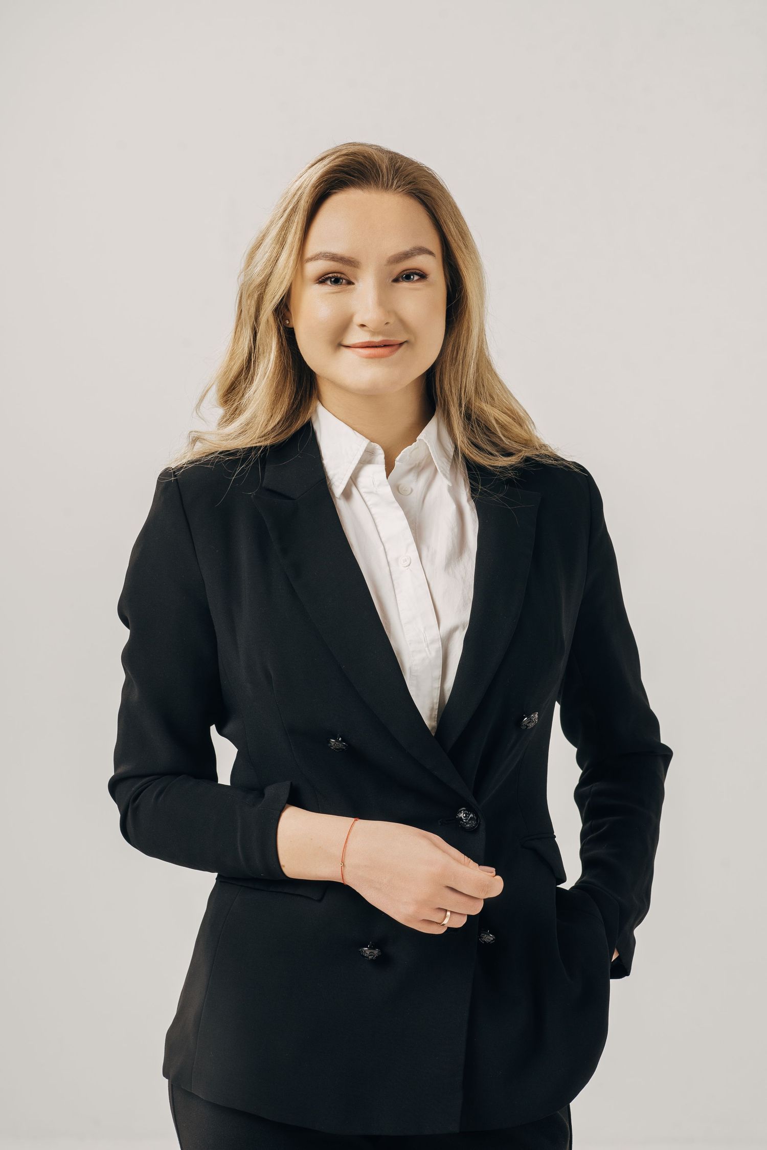 Corporate portrait series in classic black blazer and white shirt against light background.
