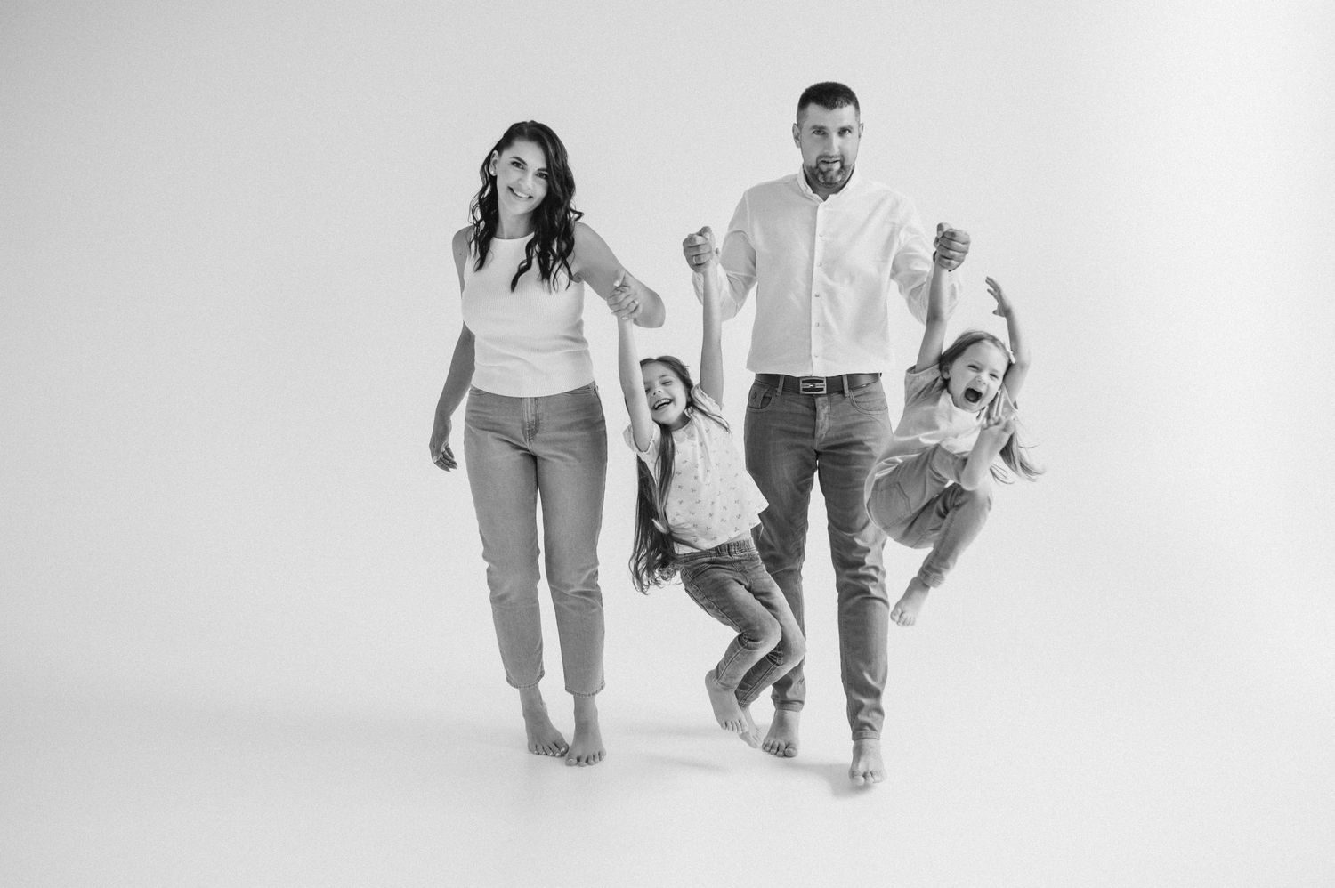 Black and white photo series showing a playful jumping sequence with family members in casual attire.