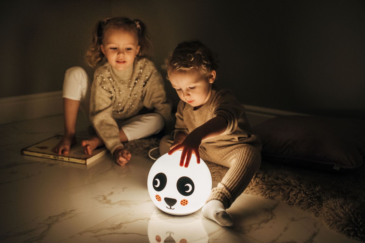 Children playing with illuminated night lights in darkened room.