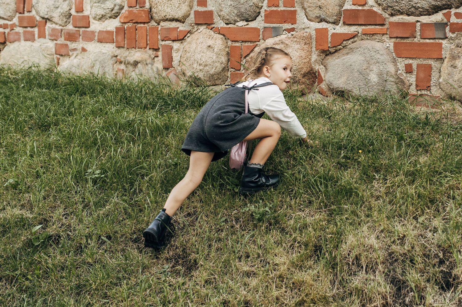 Sequential images of a person rolling down a grassy hill outdoors.