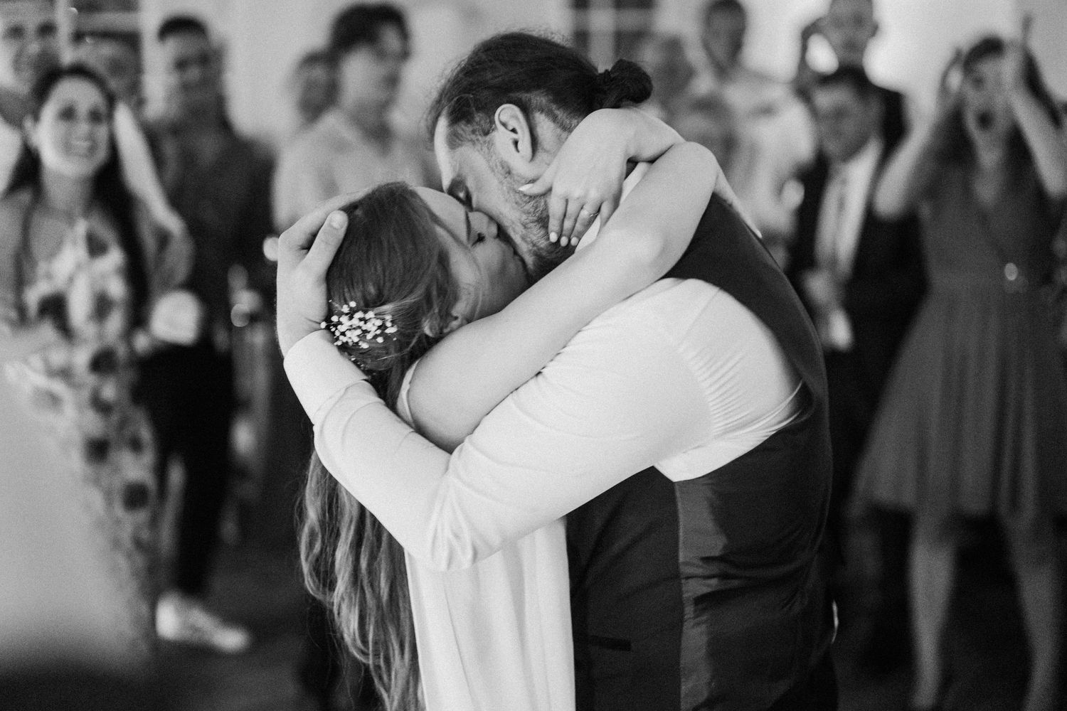 Black and white photo of wedding guests watching a romantic first dance at a reception.