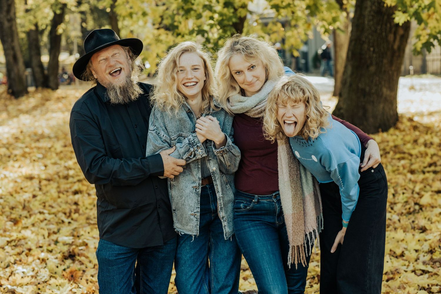 Group enjoying a candid laughing moment together outdoors in autumn weather.