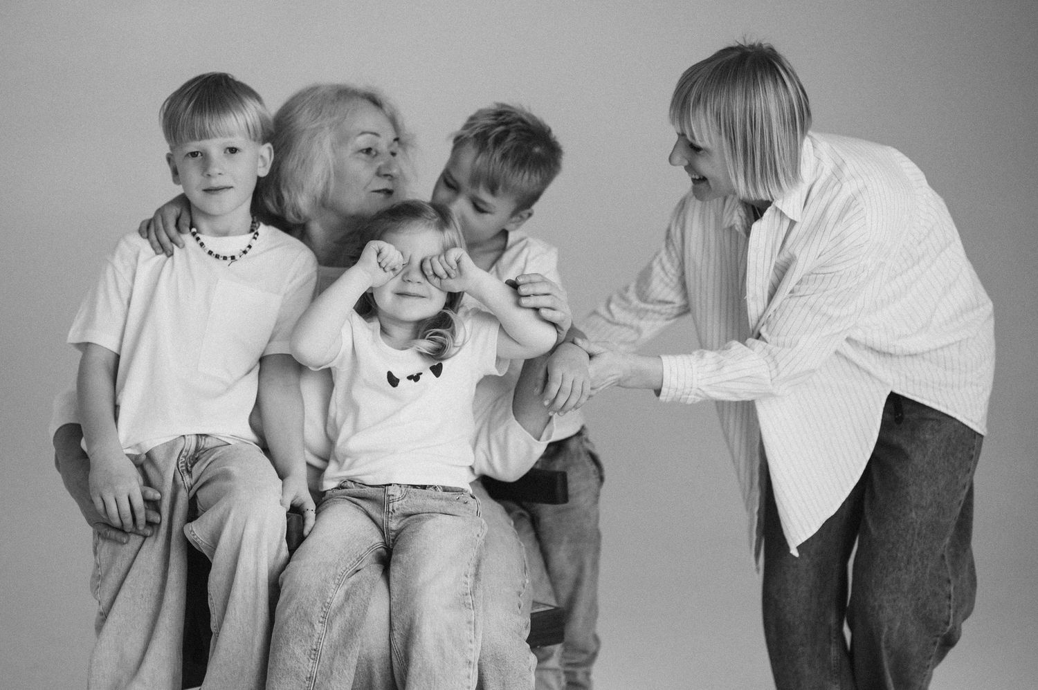 A series of black and white photos showing playful interactions between parents and children in white t-shirts.